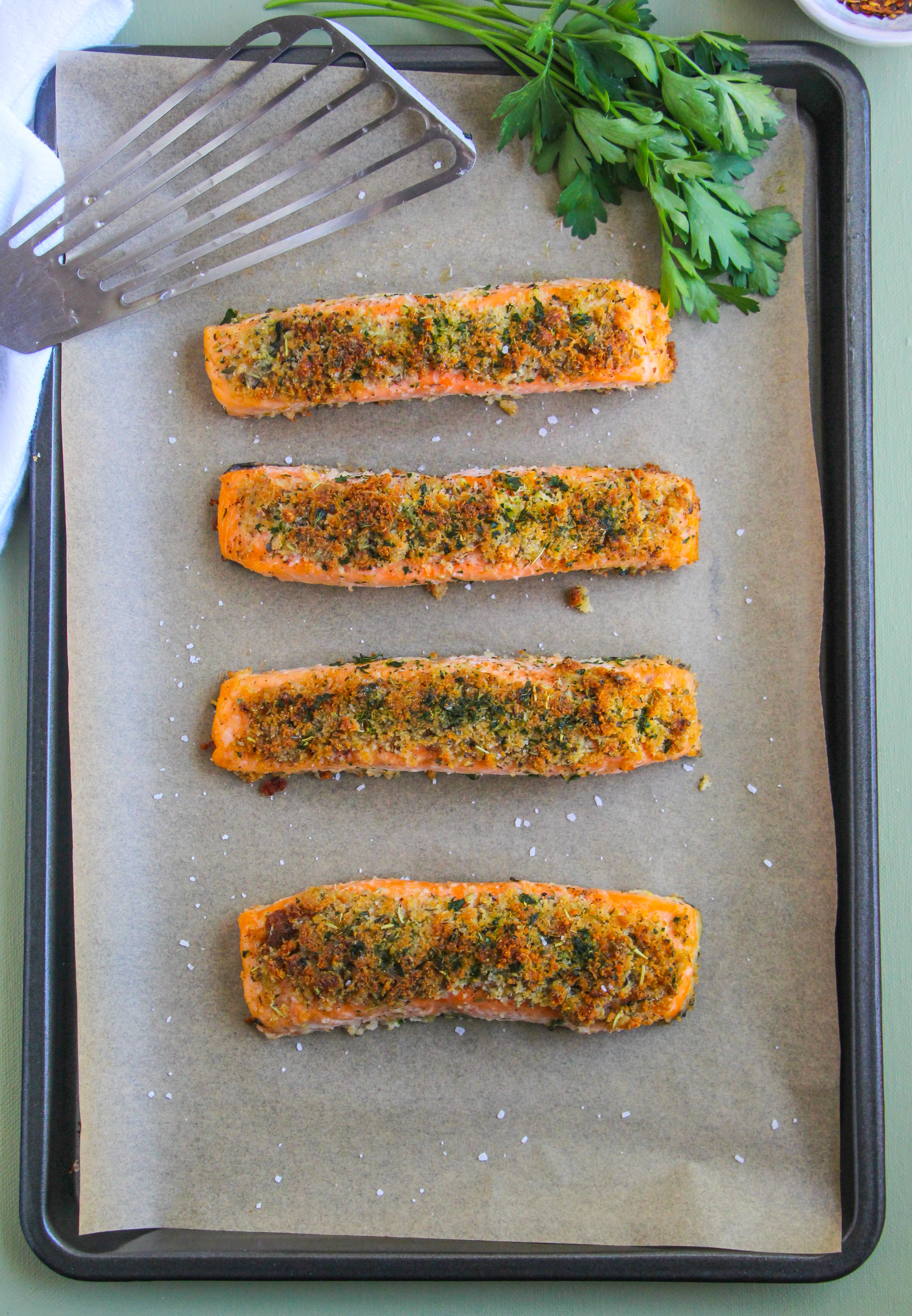Four pieces of salmon on a parchment lined sheet pan. 