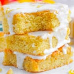 The Lemon Sugar Cookie Bars topped with lemon sugar glaze in a stack on a white plate.