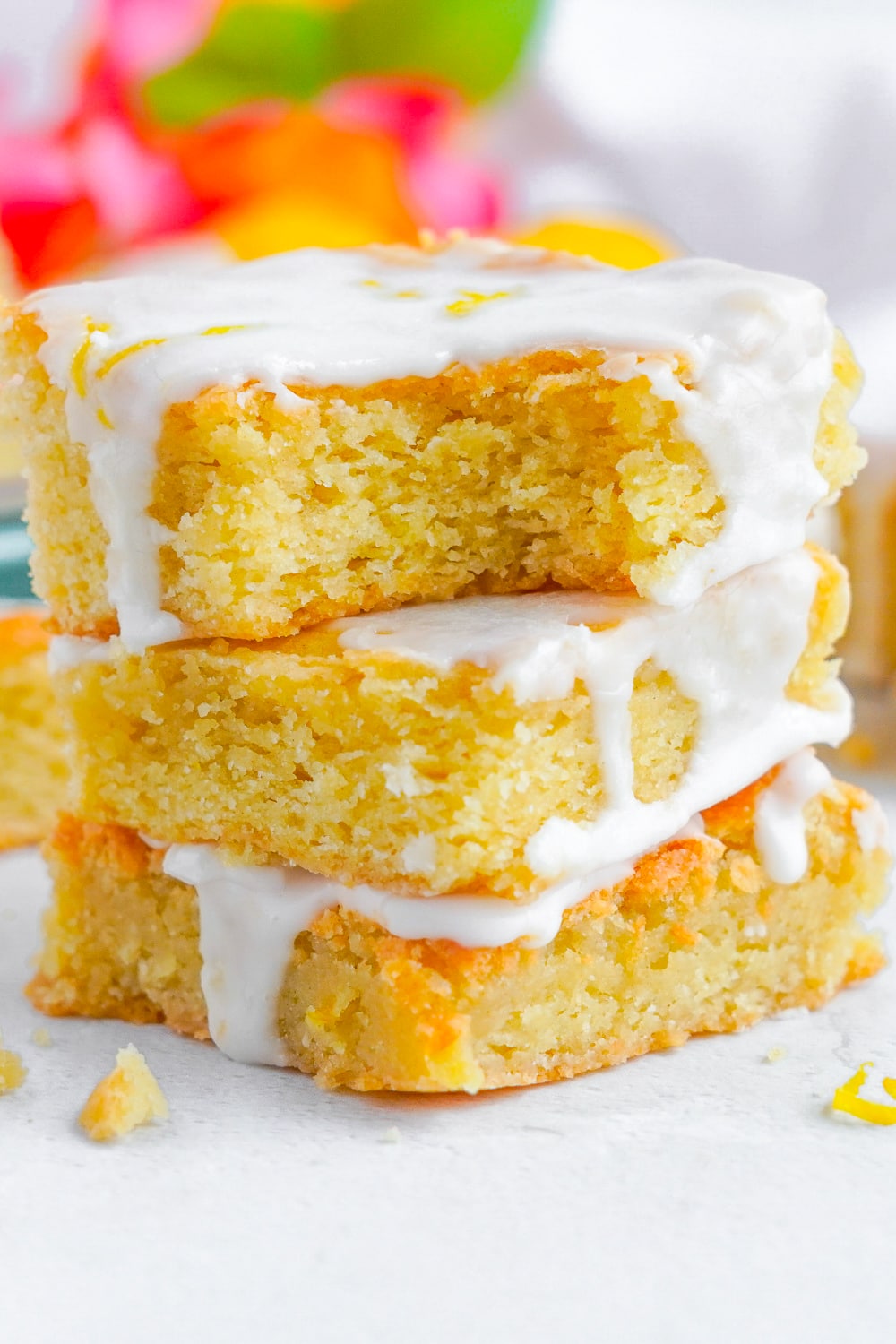 The Lemon Sugar Cookie Bars topped with lemon sugar glaze in a stack on a white plate.