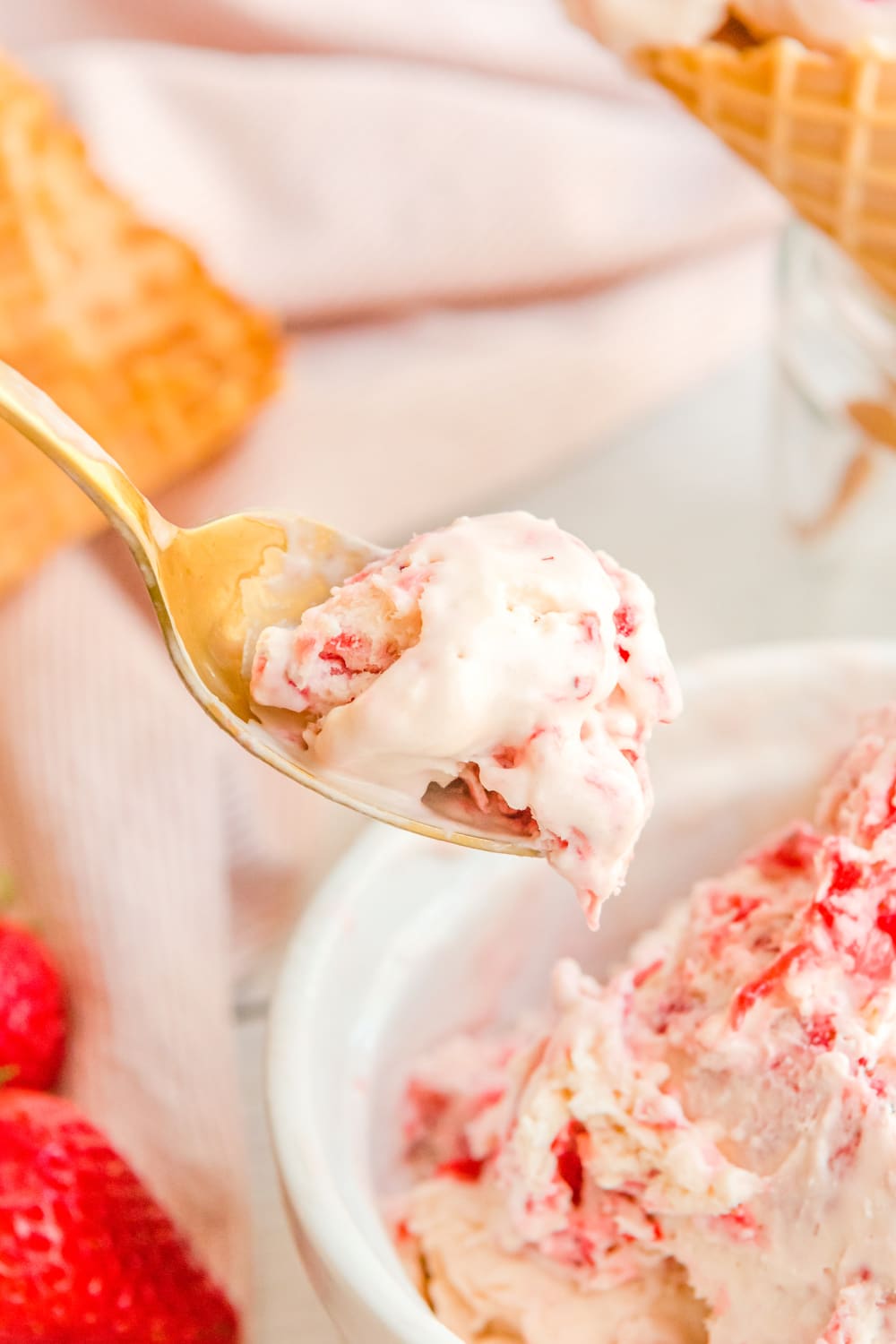 A bite of ice cream on a spoon near a bowl on ice cream.