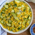 Sautéed Corn and Zucchini in a white serving bowl on a wood background.