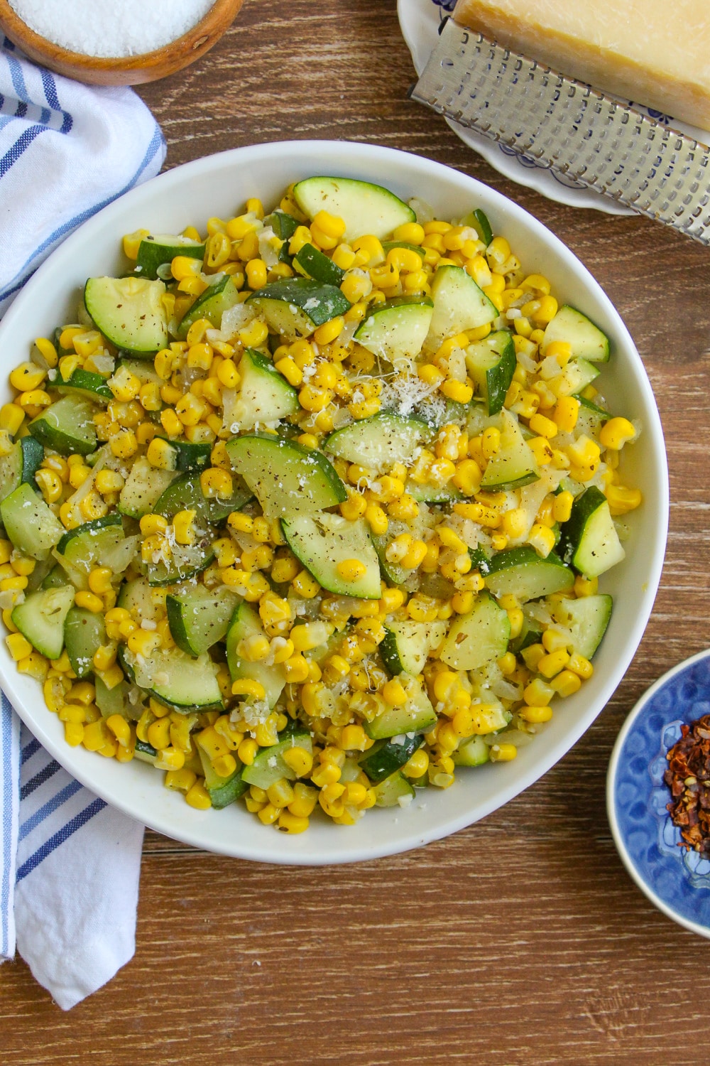 Sautéed Corn and Zucchini in a white serving bowl on a wood background.
