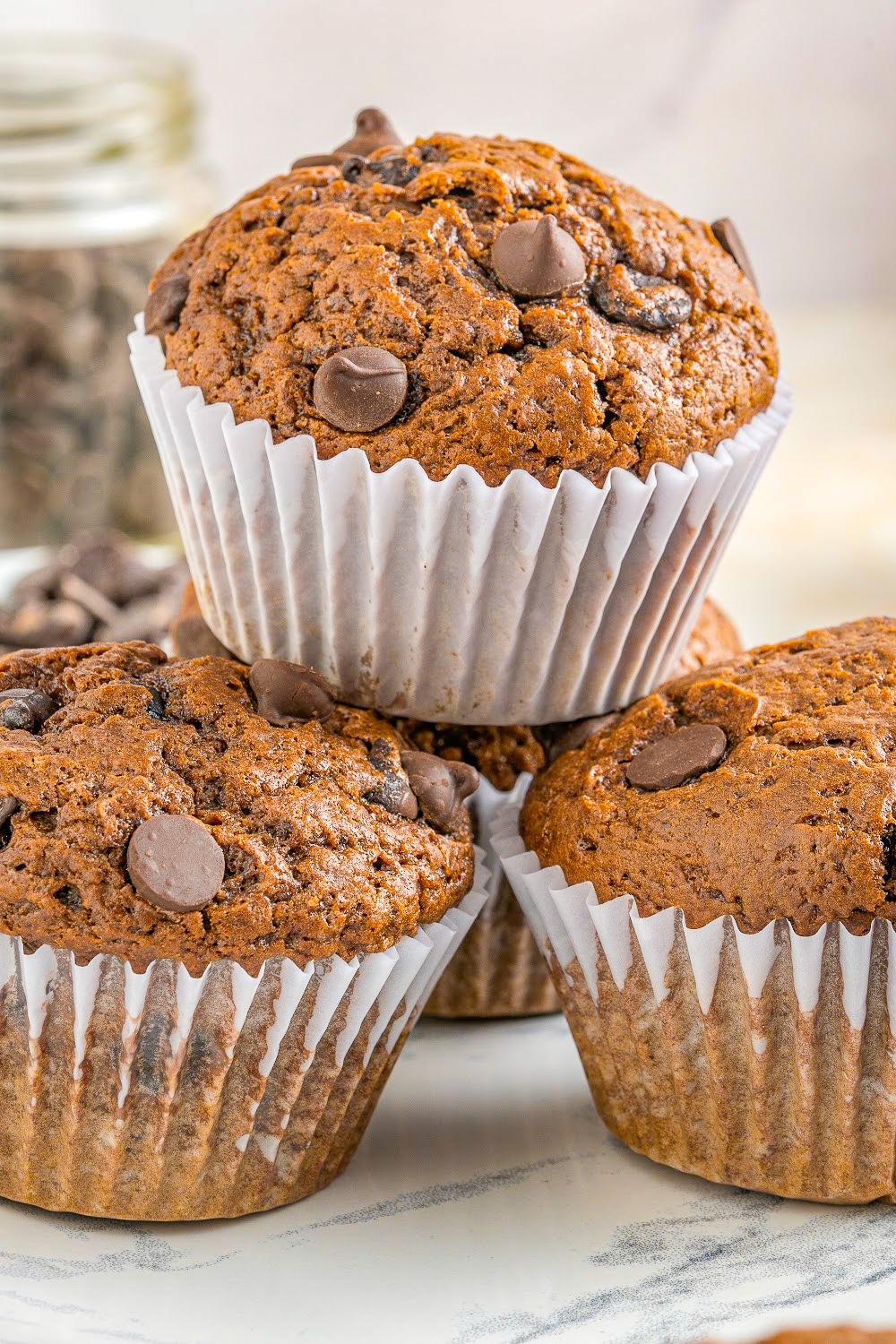 Three muffins in white paper liners stacked in a pyramid.