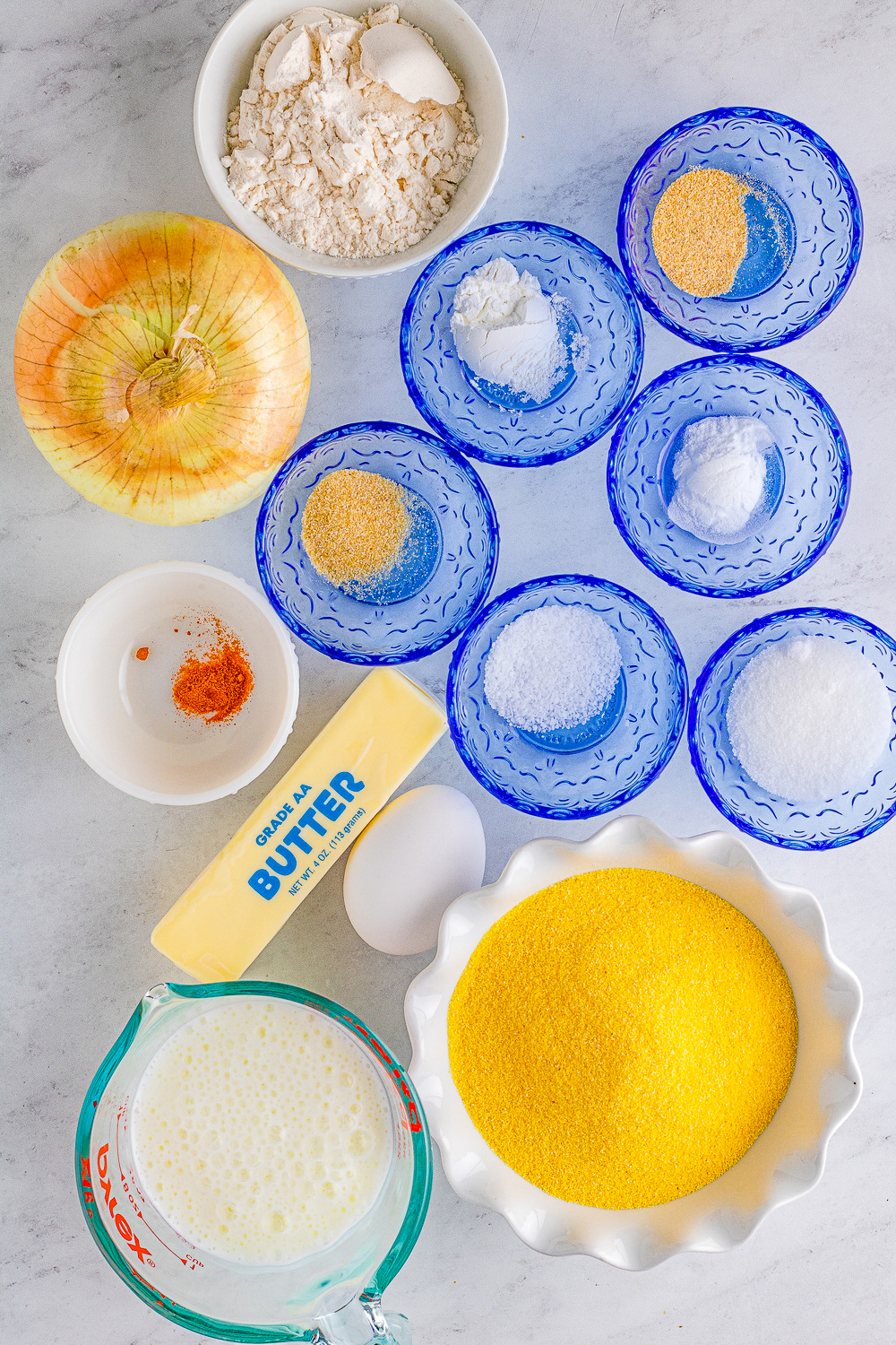 Pre-measured ingredients needed for this recipe presented in blue glass pinch bowls one a white marble countertop.