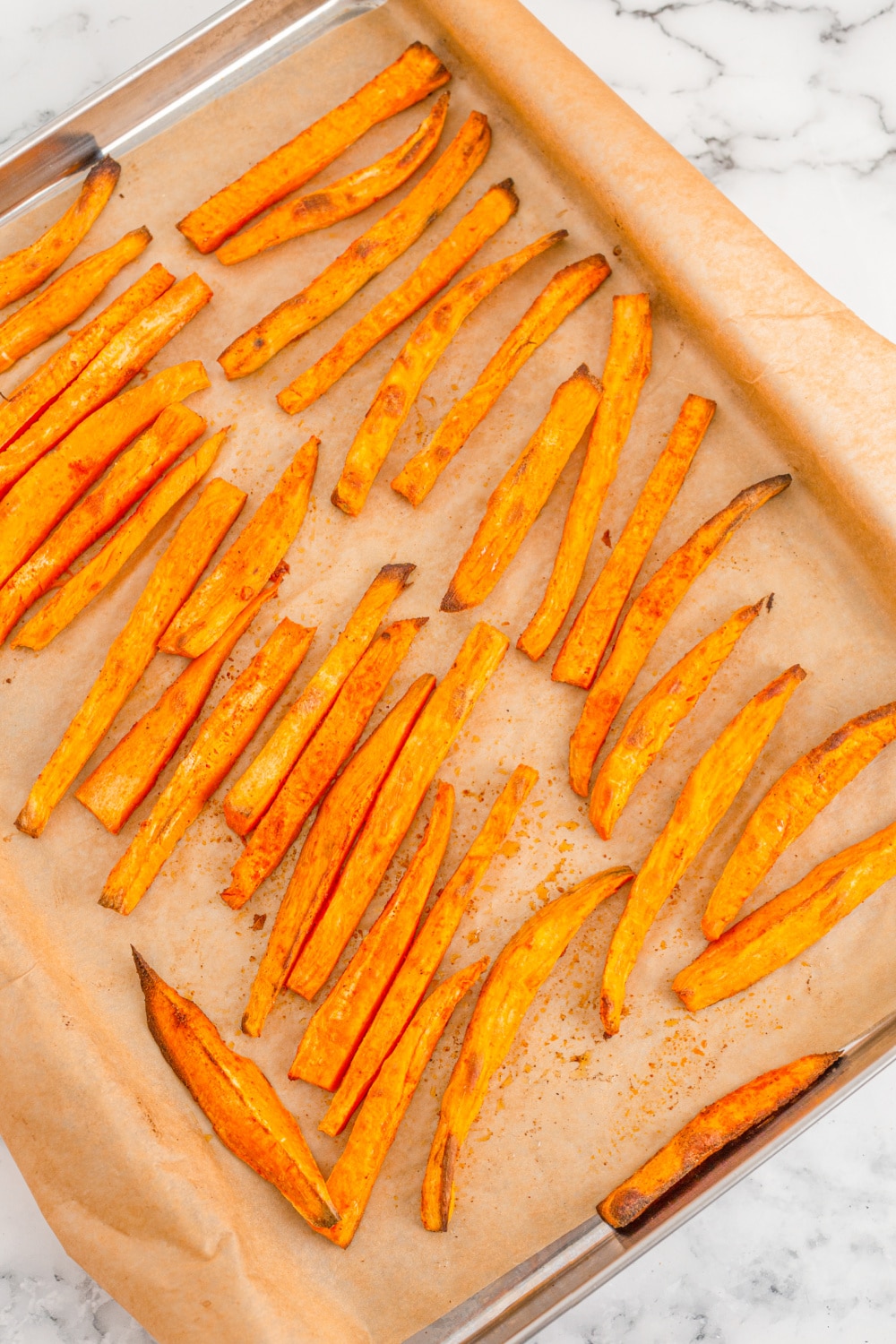 Sweet Potato Fries from the oven on a baking sheet lined with parchment paper.