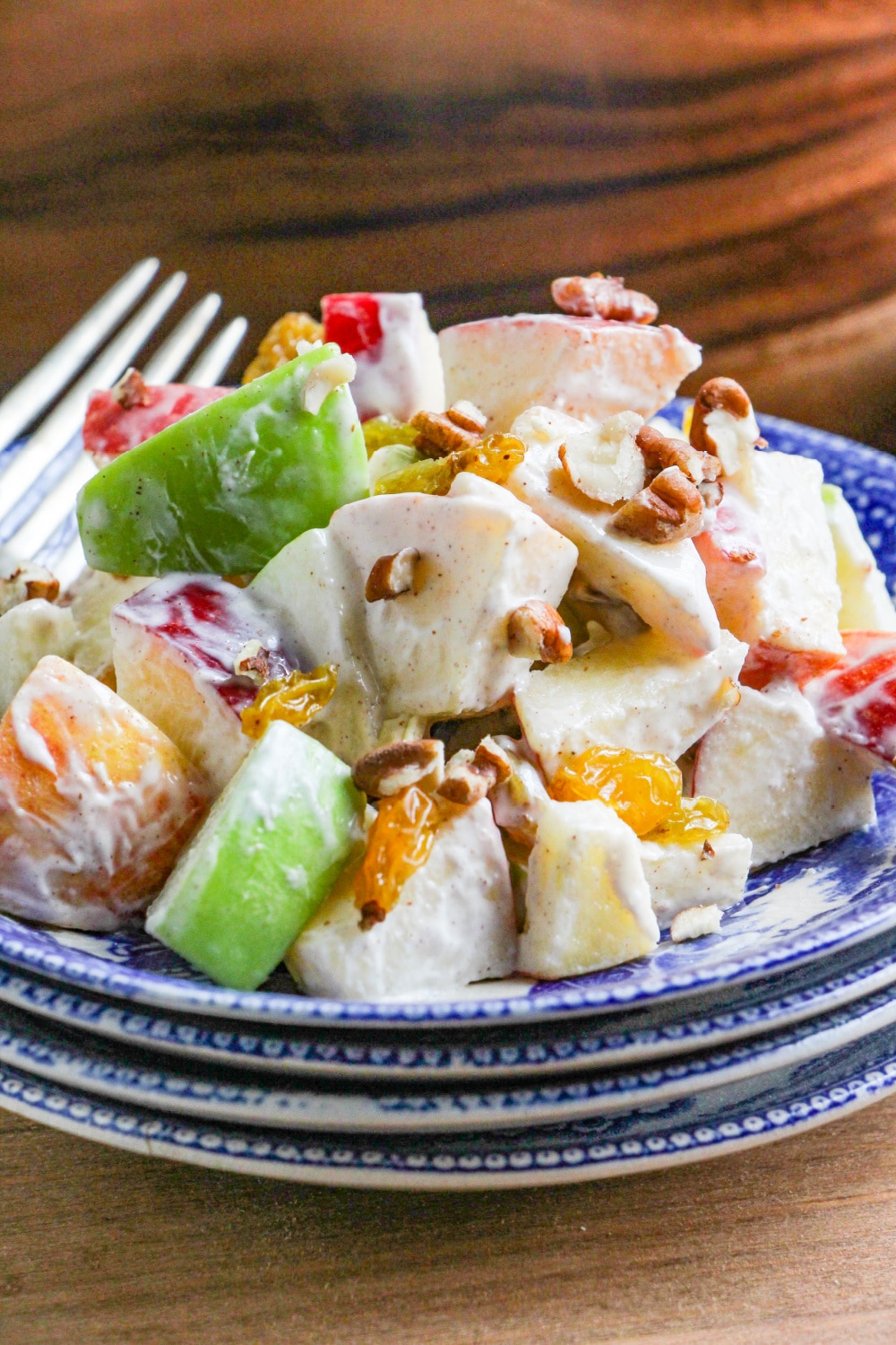 A scoop of Apple Salad on a blue and white plate with a fork resting on the side.