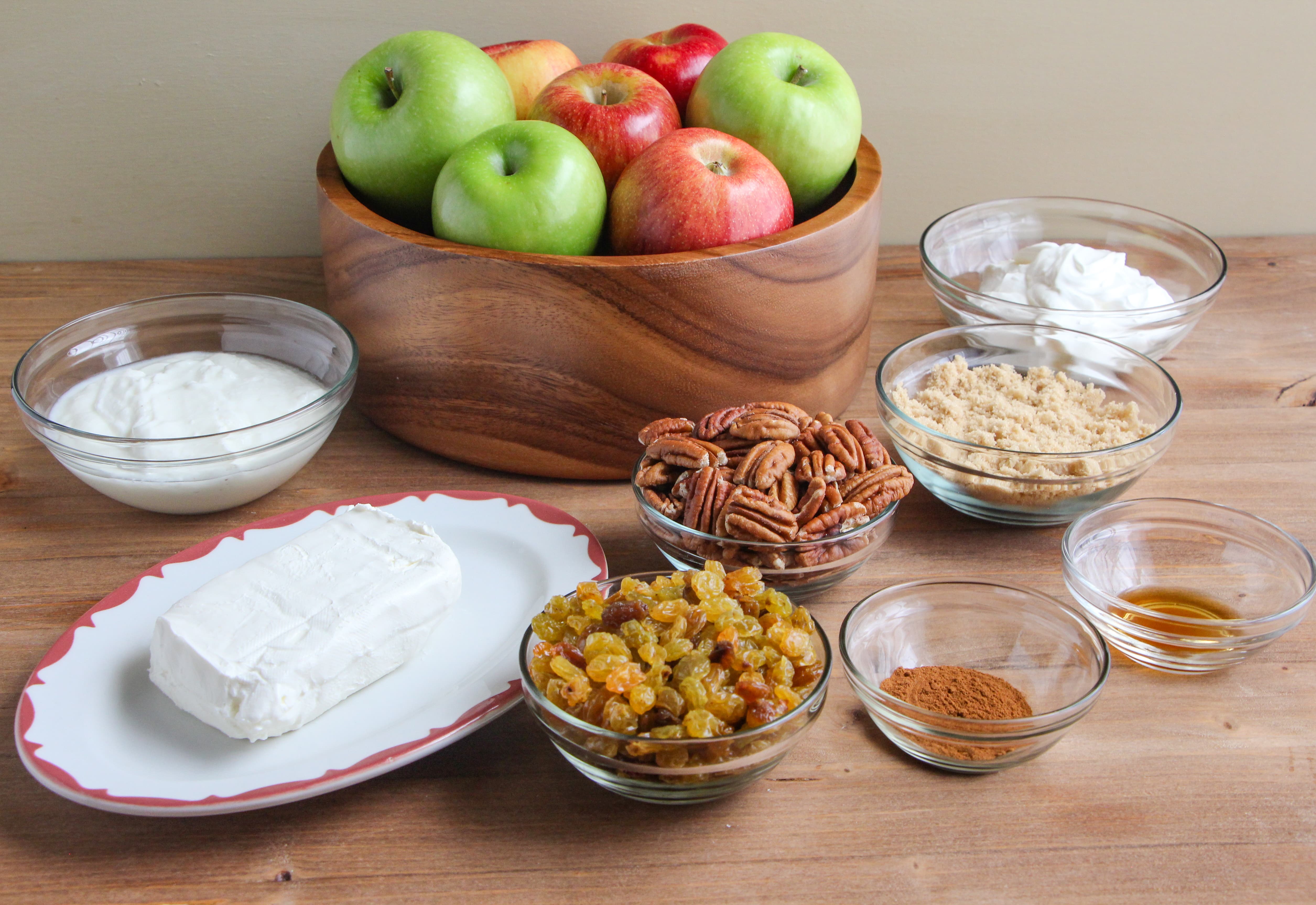 Ingredients needed to make Creamy Apple Salad presented on a wooden tabletop.