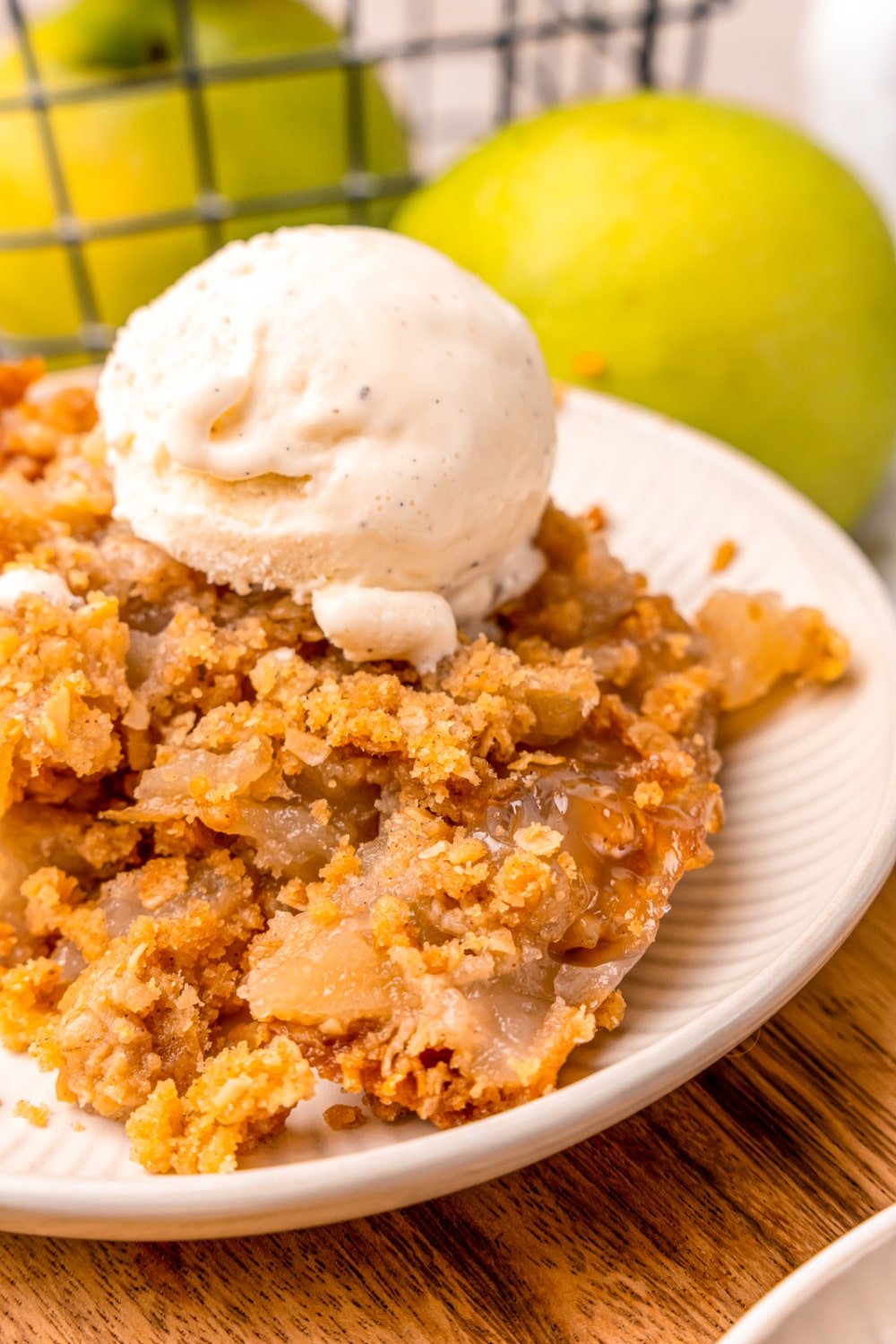 A bowl of baked Apple Crisp topped with a scoop of vanilla ice cream.