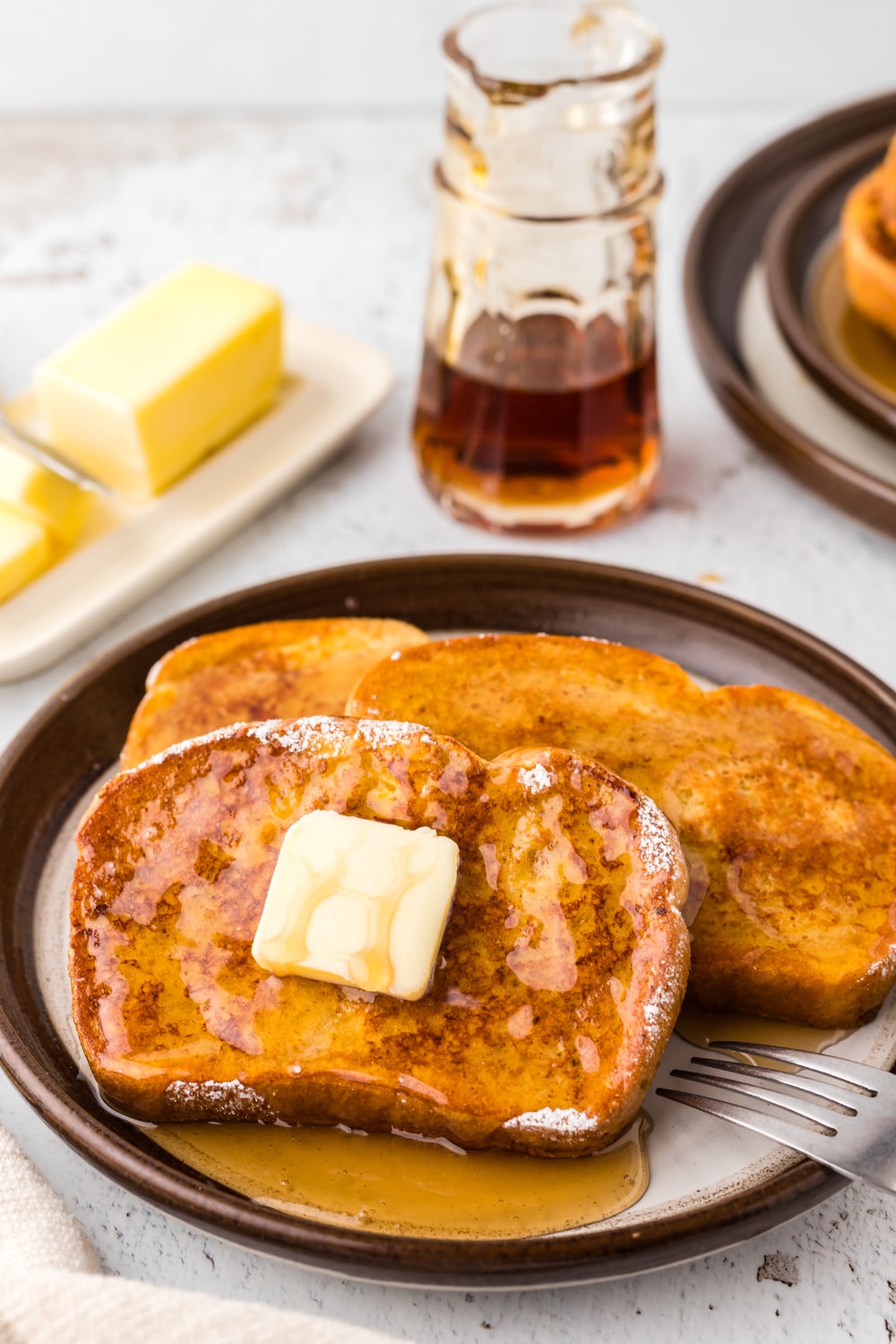 Three slices of French Toast with maple syrup and a pat of butter.