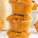 Three pumpkin muffins stacked together on a white marble counter top.
