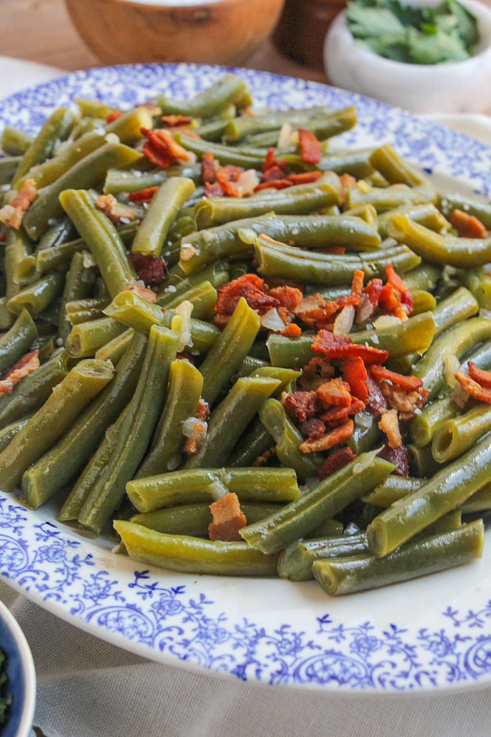 Southern Style Green Beans on a blue and white platter garnished with crispy bacon