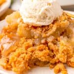 Apple Crisp topped with vanilla ice cream served on a white dessert plate.