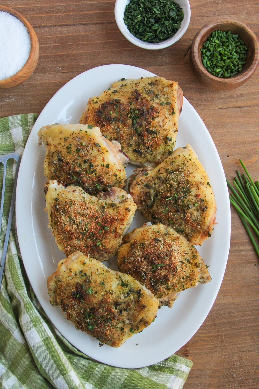 Chicken Thighs on a white platter garnished with fresh chives.