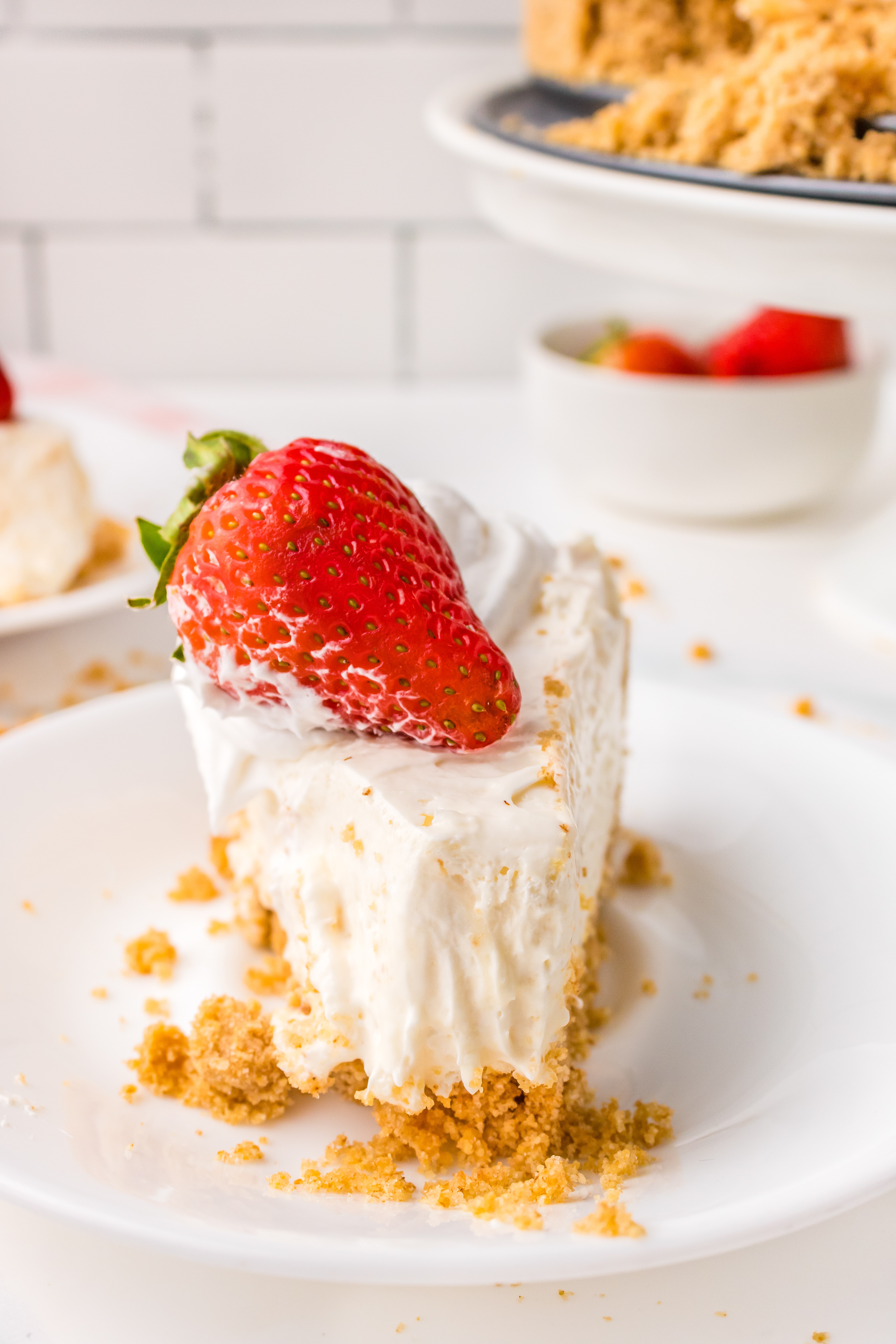 Cheesecake with graham cracker crust on a white plate.