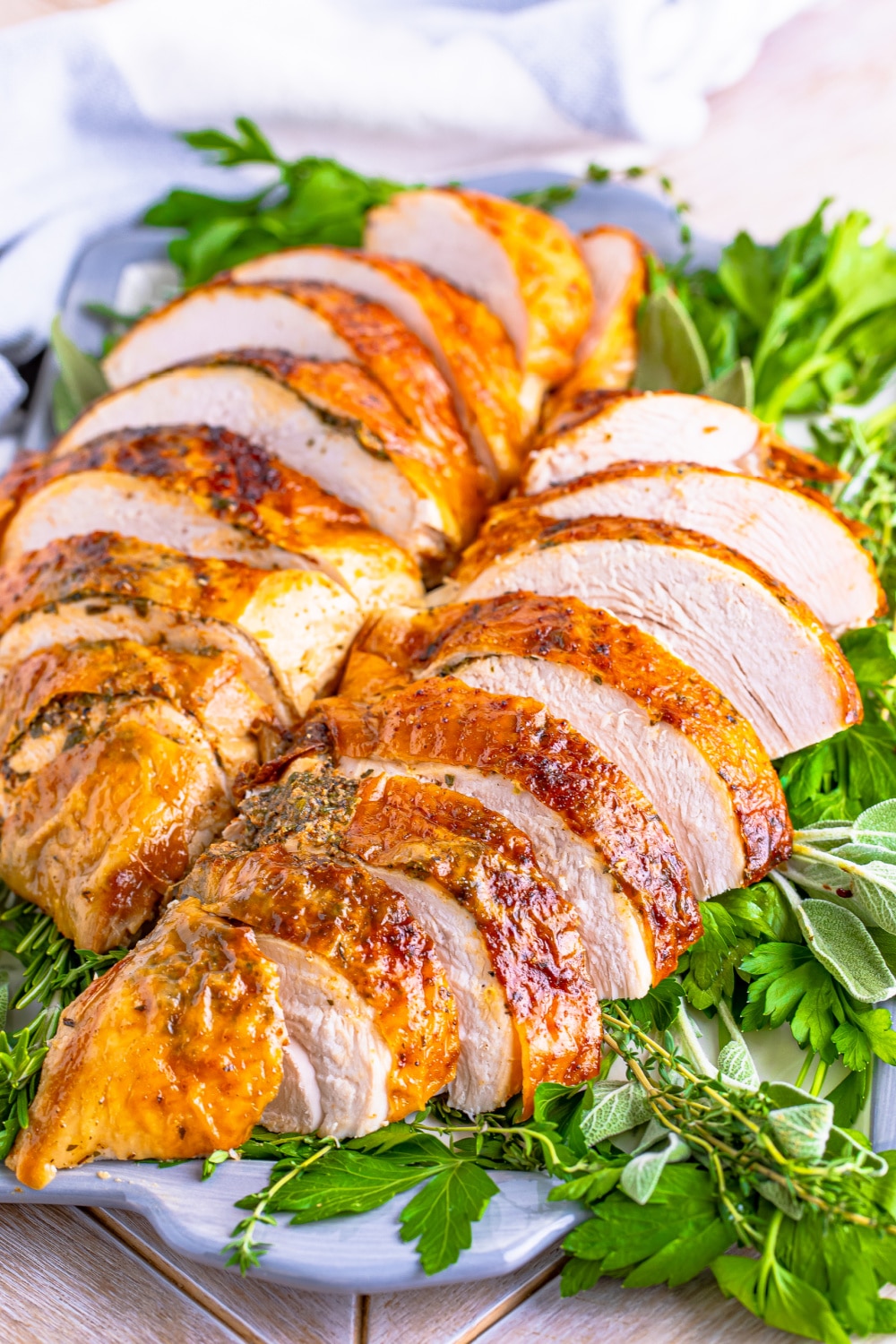 A turkey breast that has been sliced lays on a bed of greens.