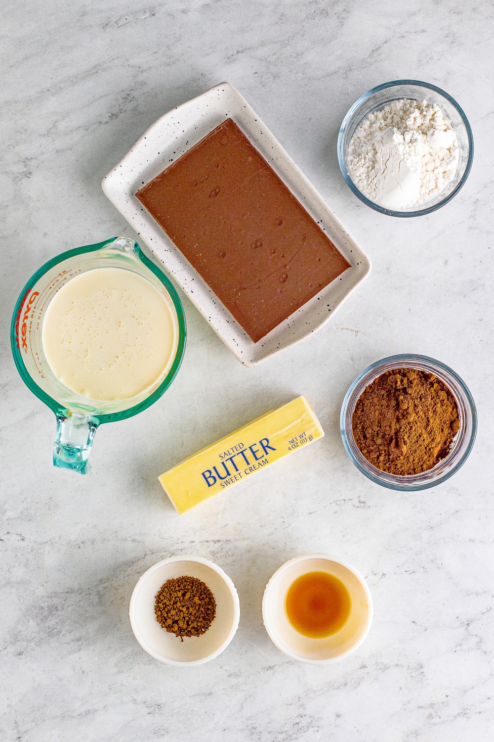 Measured ingredients needed to make chocolate mousse presented on a white marble countertop.