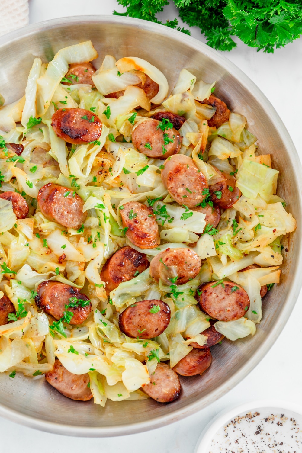 Fried cabbage and kielbasa sausage in a white bol.