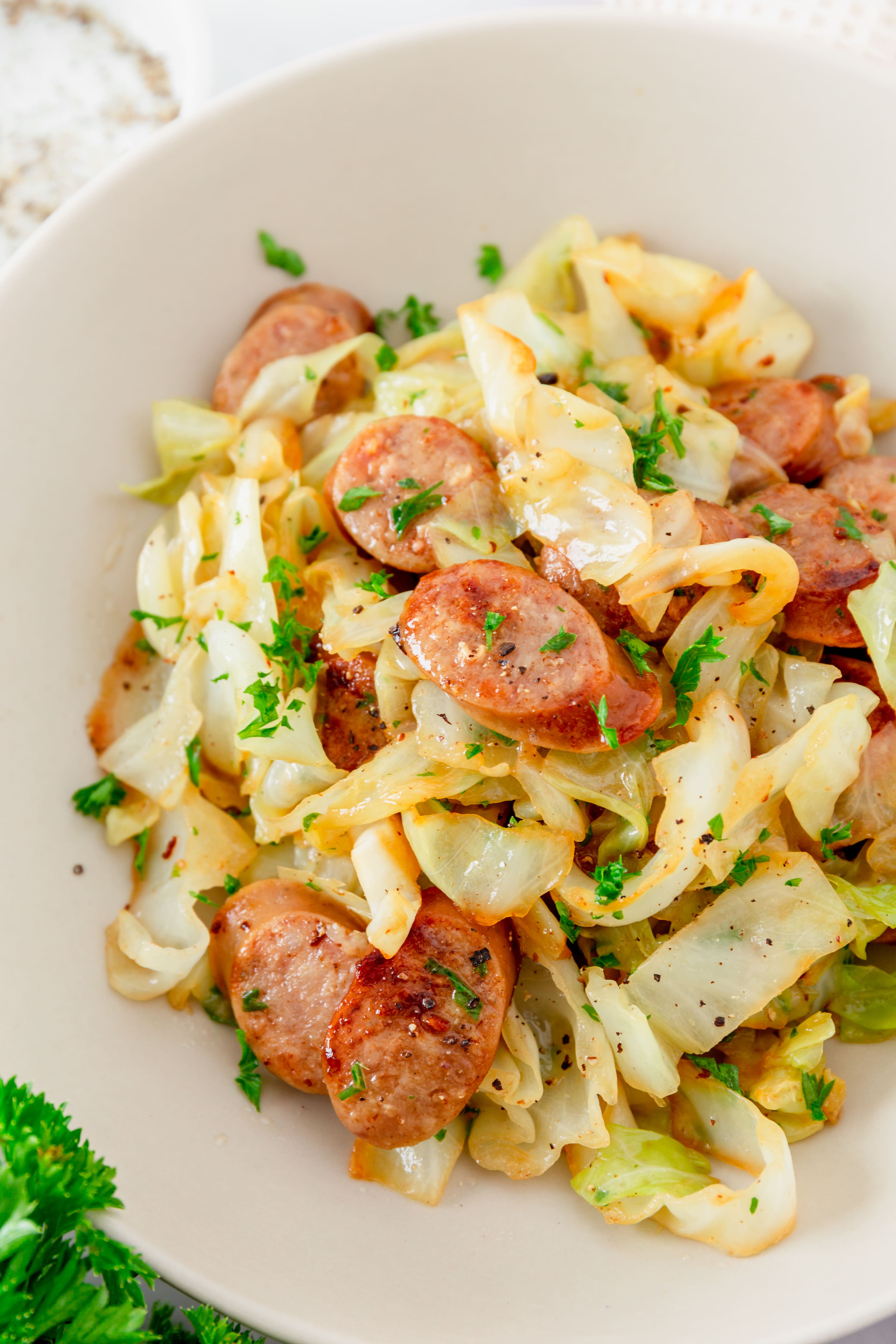 Prepared cabbage and sausage in a white bowl.