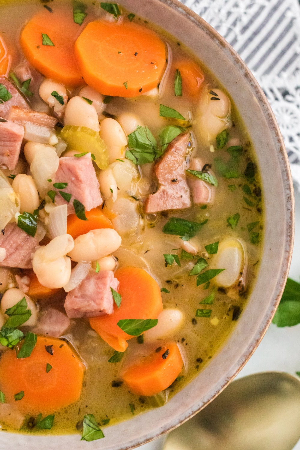 A bowl of soup filled with beans and ham.