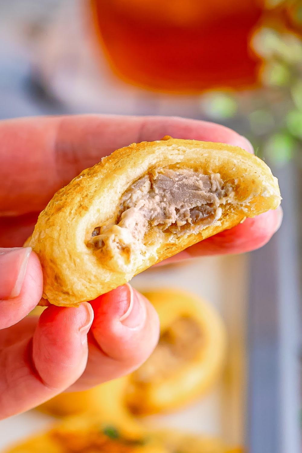 A French Dip Crescent Roll with a missing bite held in a lady's hand. 