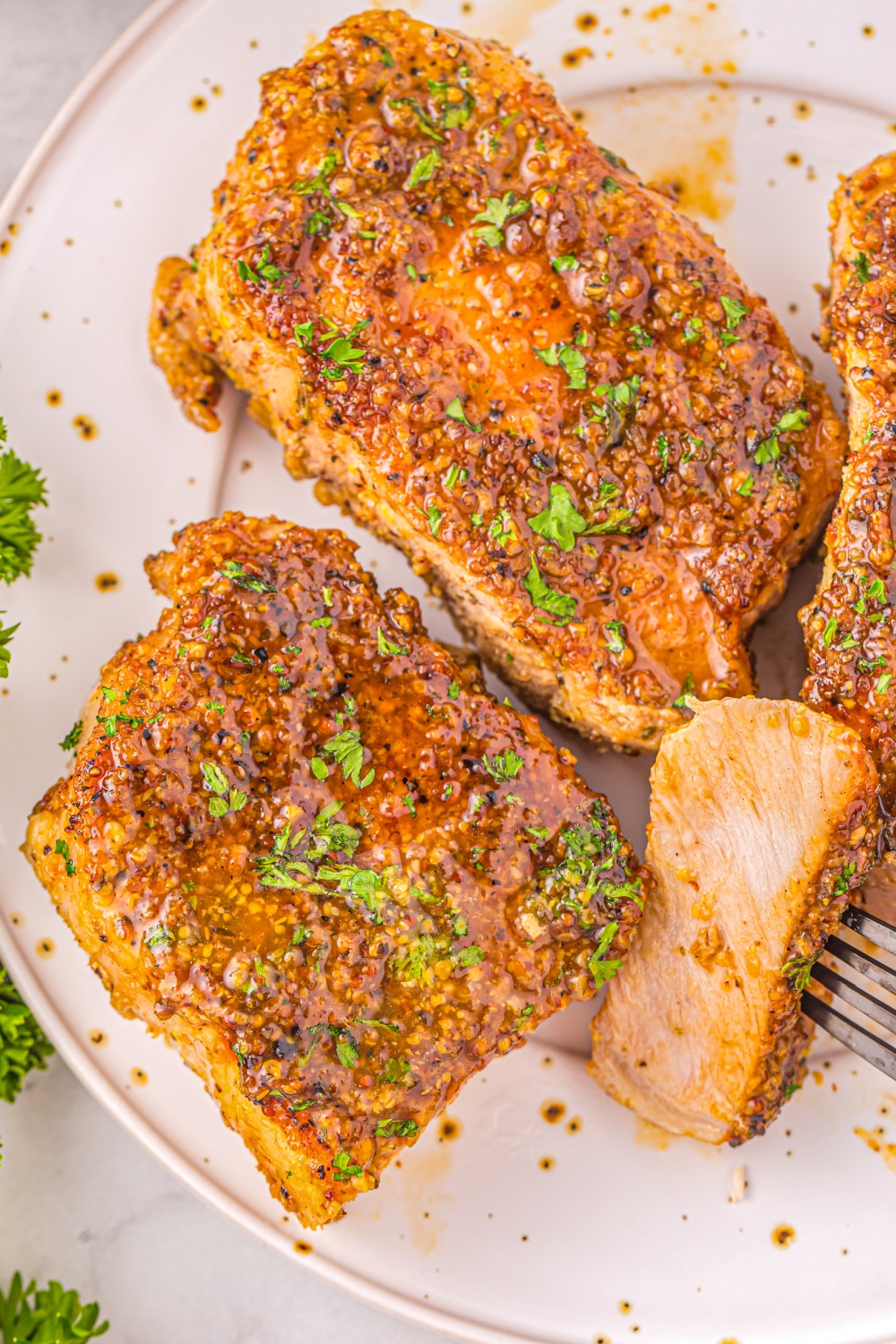 Pork Chops on a white plate with Honey Mustard Glaze garnished with parsley.