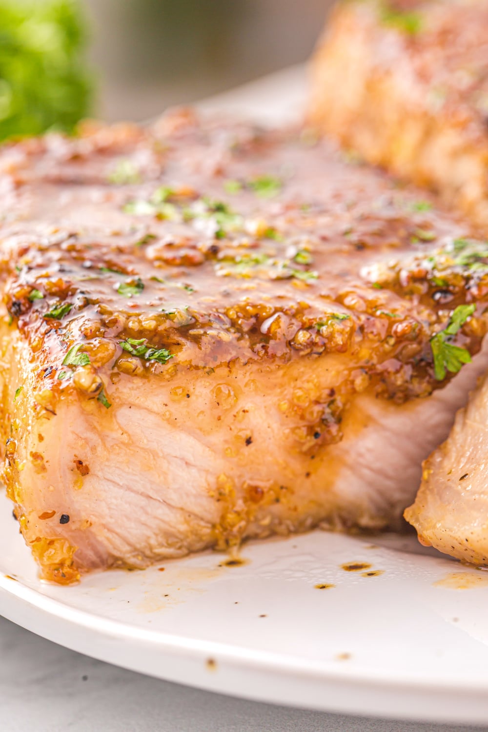 A pork chop topped with glaze sliced to reveal the tender inside of the chop.