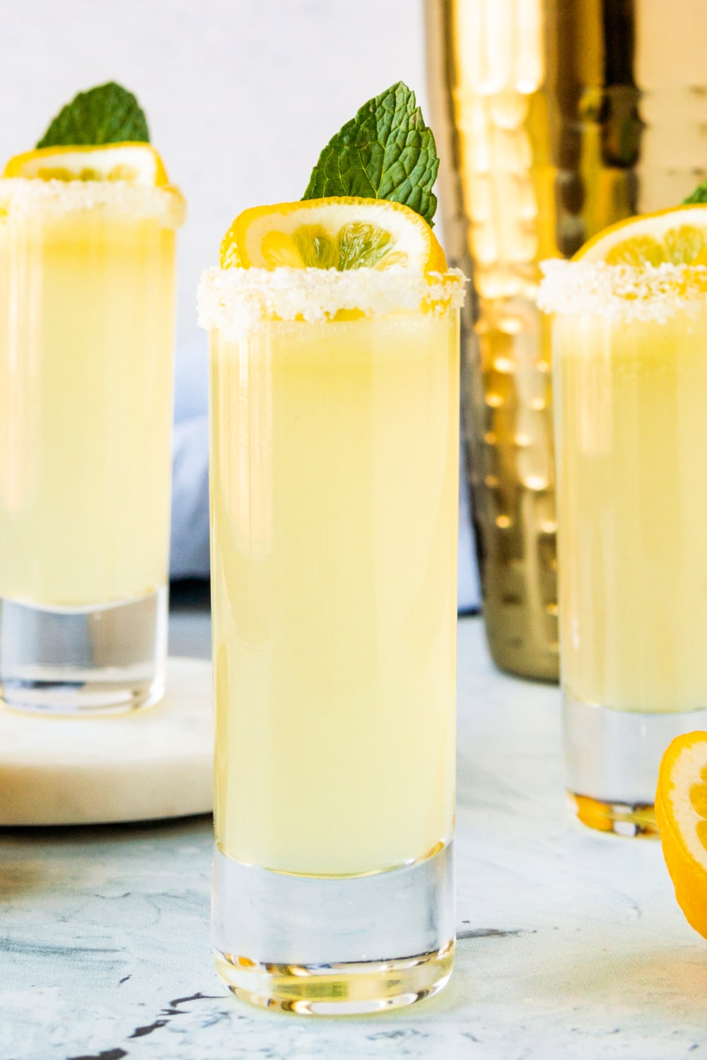 Three Lemon Drop Shots with lemon and sugar rims in tall shot glasses.