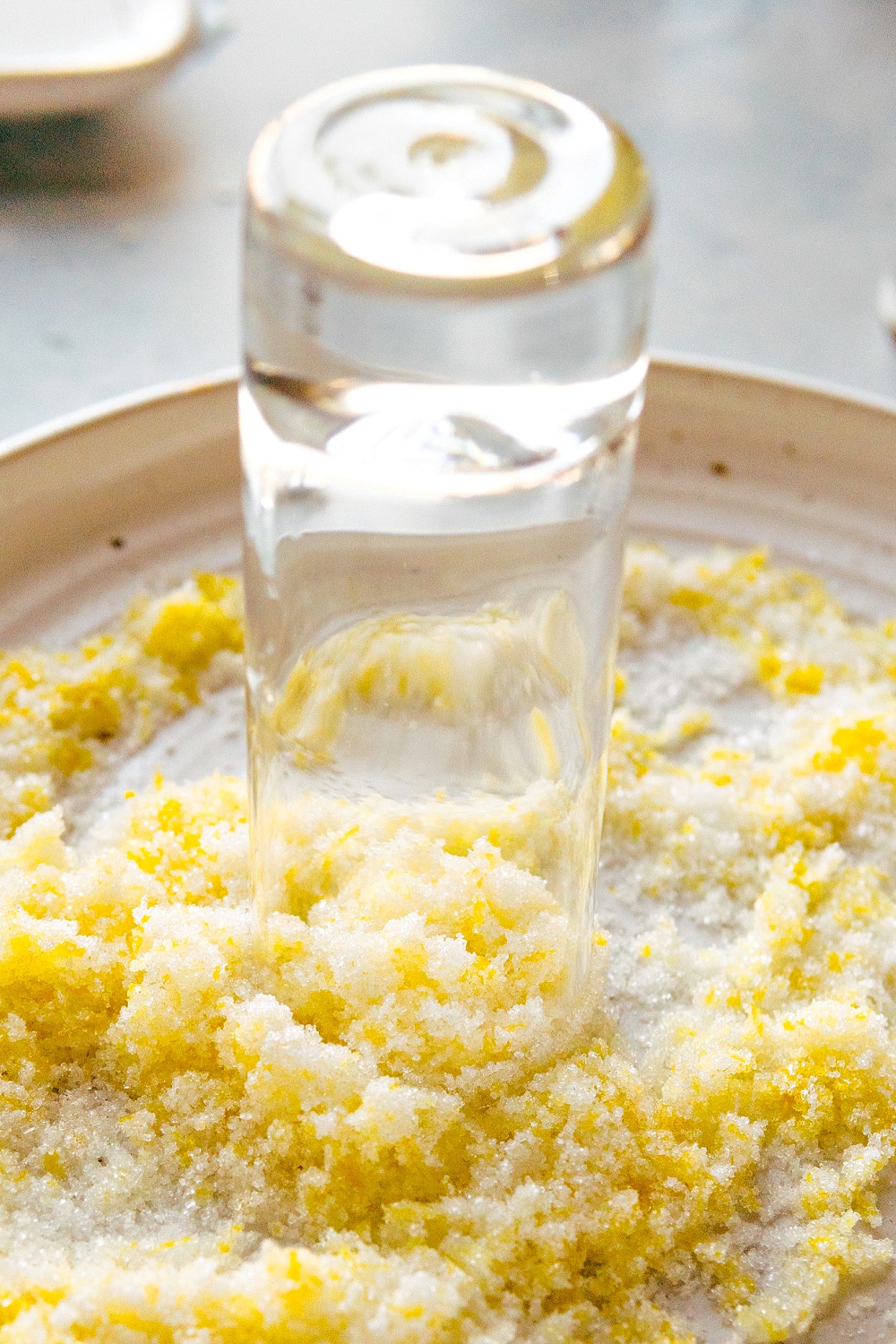 Shot glass rim being dipped into the lemon zest and sugar mixture.