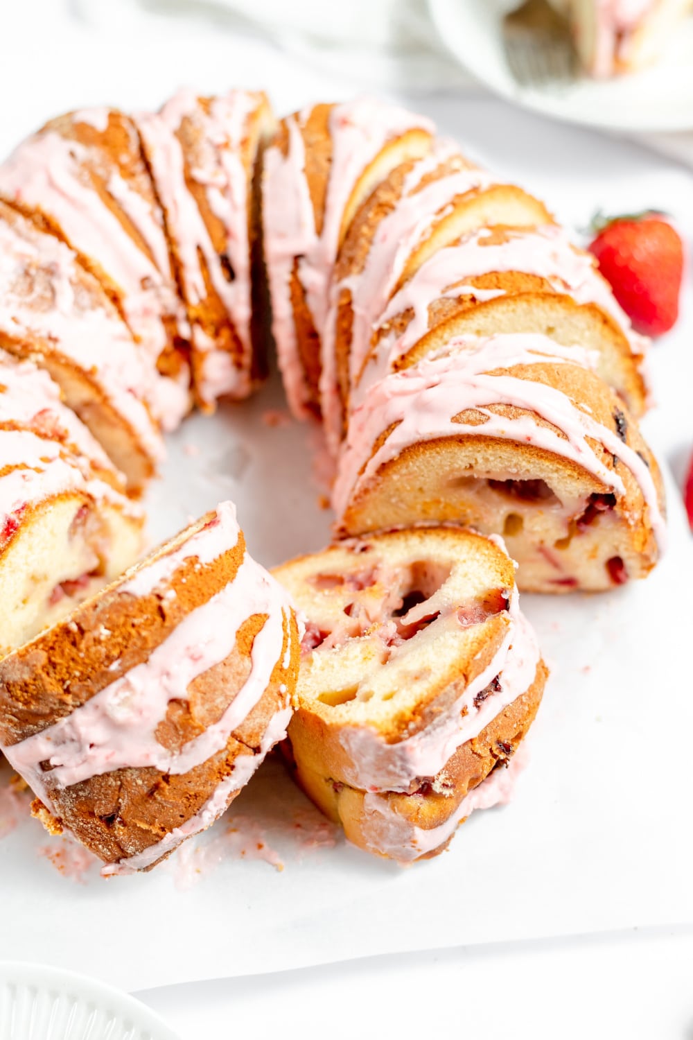Bundt cake with fresh strawberries and pink glaze.