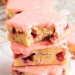 Three Strawberry Lemon Blondies stacked one on top of the other on a white plate.