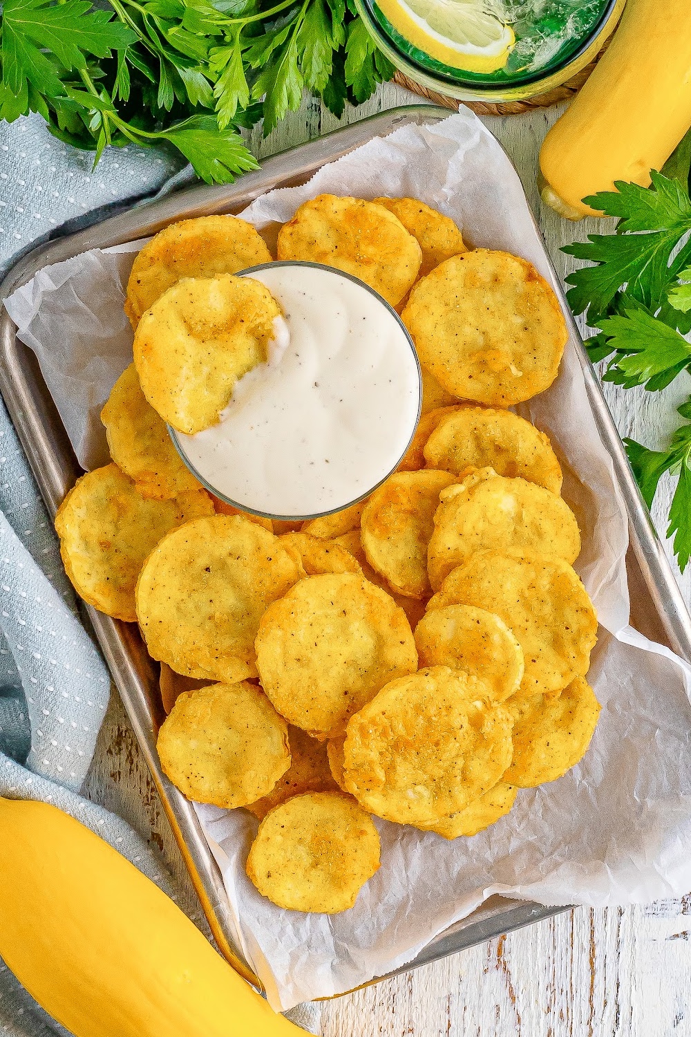 Fried Squash piled on a small tray with a bowl of ranch dressing for dipping.