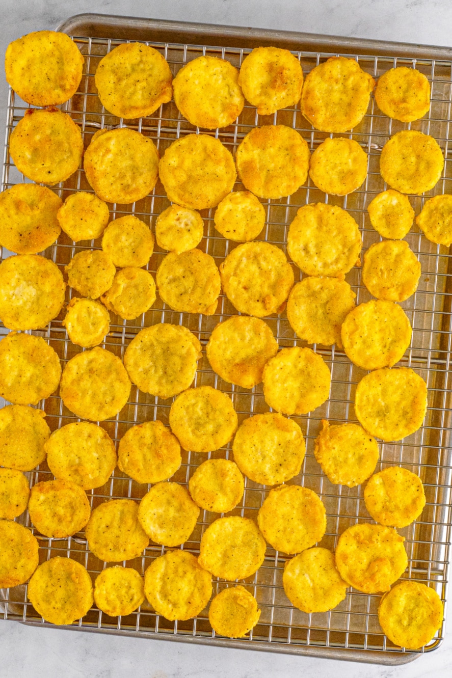 Freshly fried squash on a cooling rack over a sheet pan.