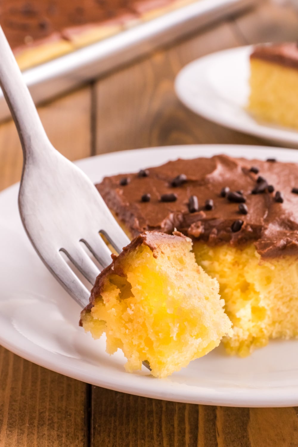 A single bite of Yellow Sheet Cake with Chocolate Frosting on a fork.