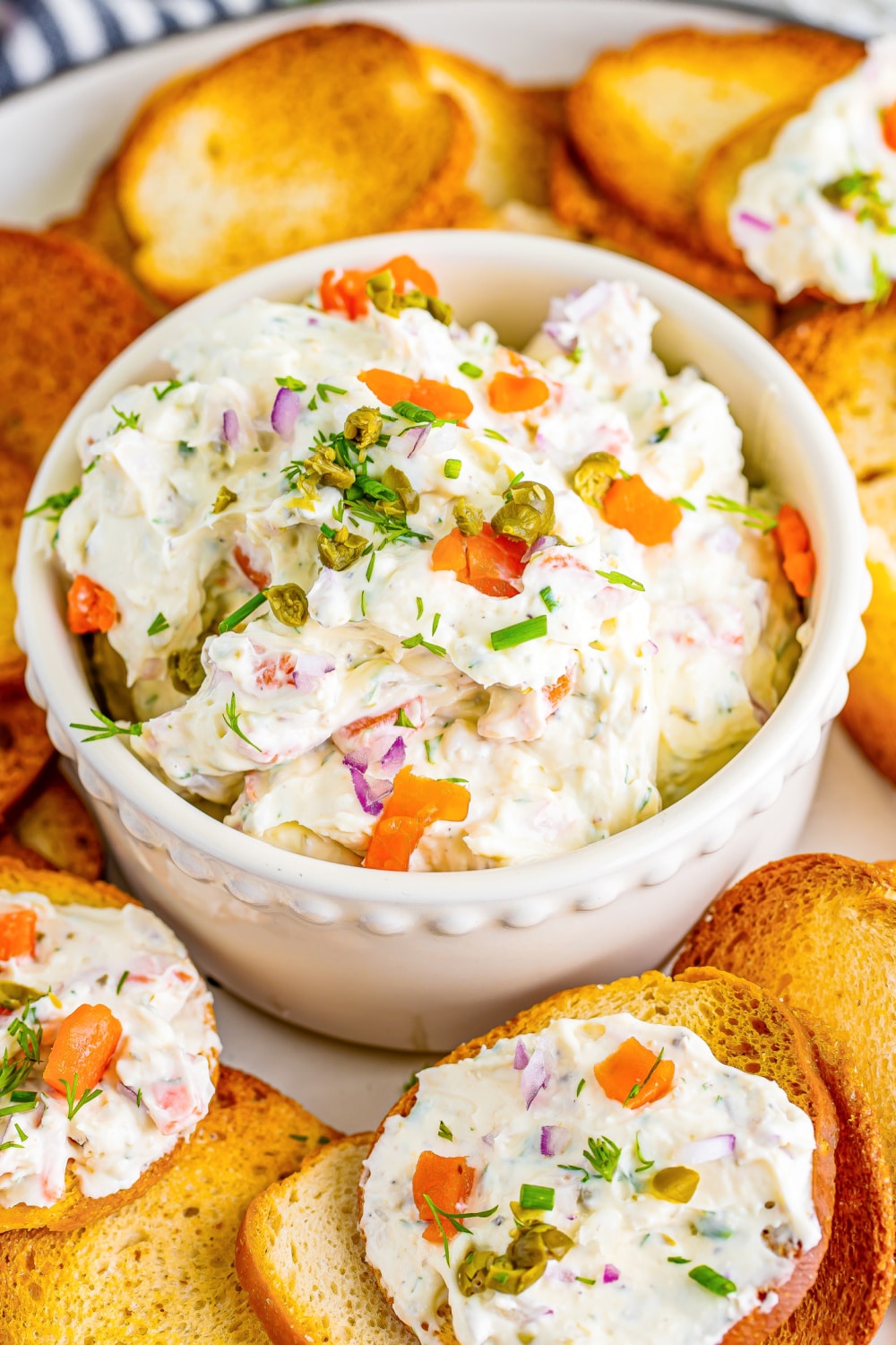 A white bowl of Salmon Dip on a platter surrounded by toast points.