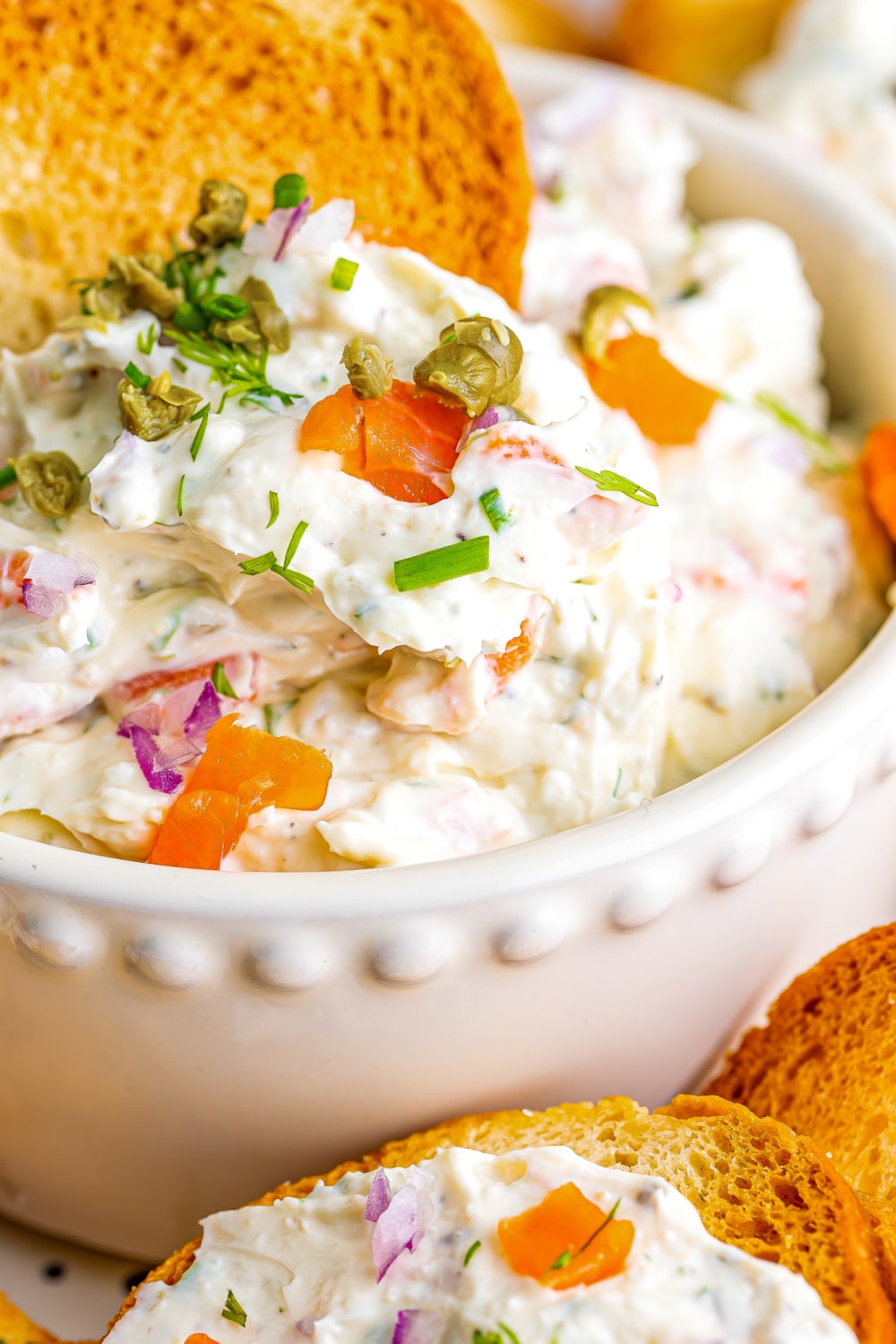 Smoked Salmon Dip in a white bowl garnished with fresh dill and pieces of smoke salmon.
