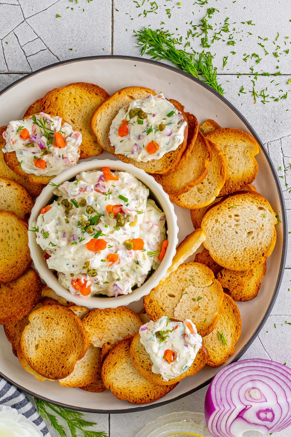 Creamy salmon dip in a white bowl on a white platter with toast points.