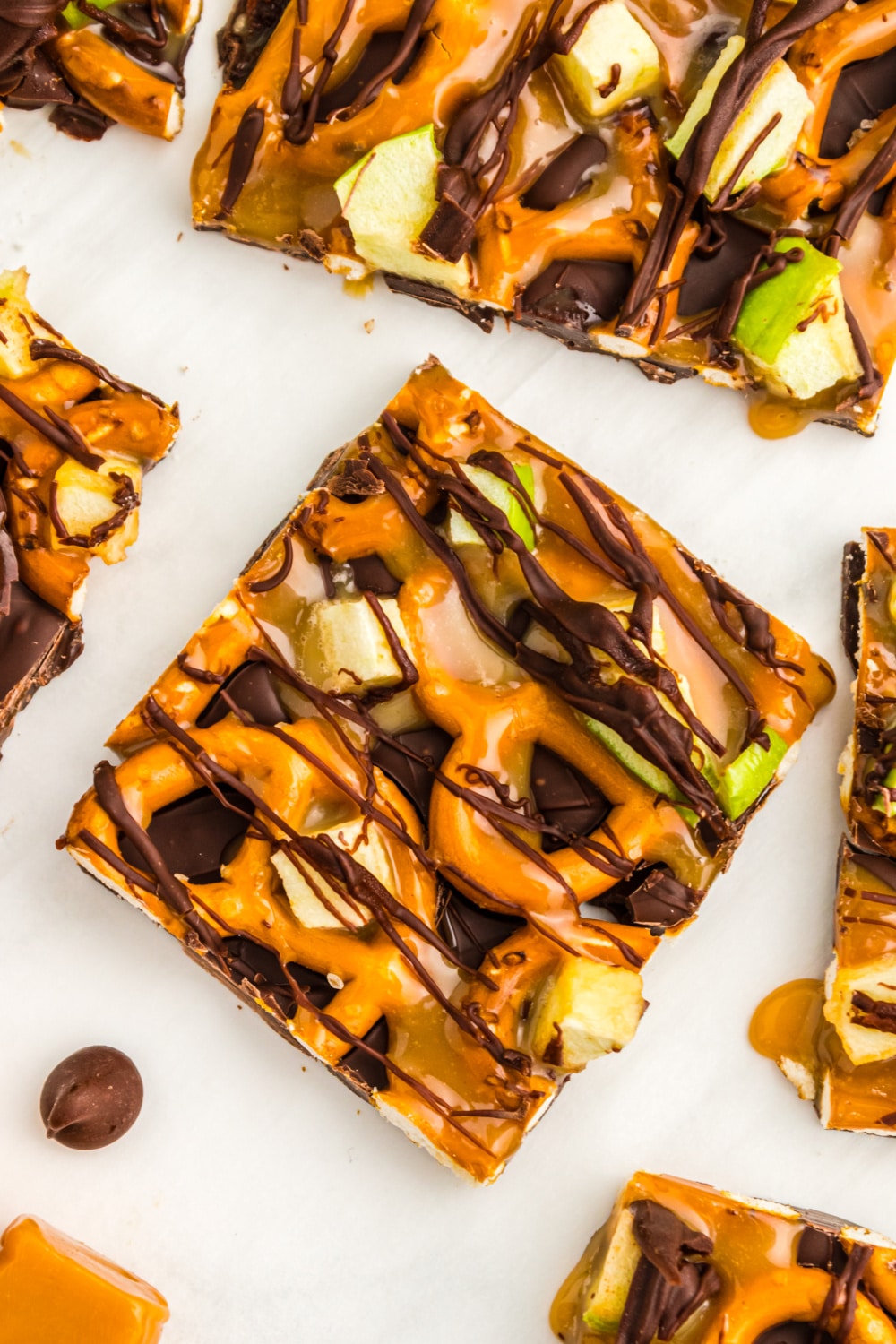 Caramel Apple Bark cut into squares lays on white parchment paper.