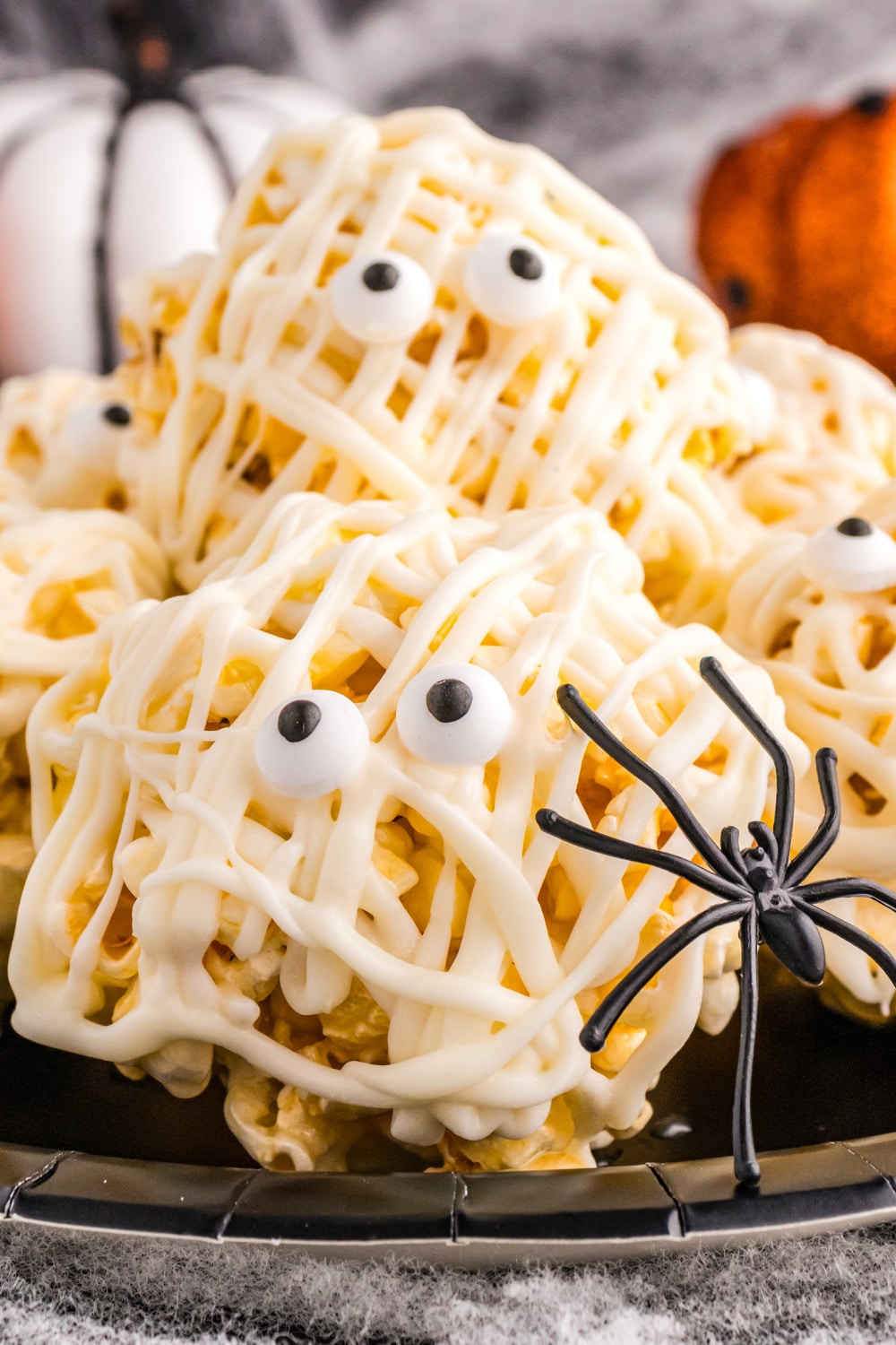 Halloween Popcorn Balls on a black plate with a toy spider climbing along the side.