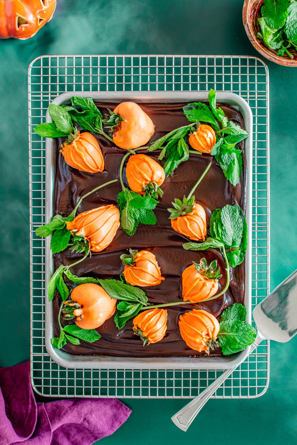 A pan of brownies decorated like a pumpkin patch sits on a cooling rack.