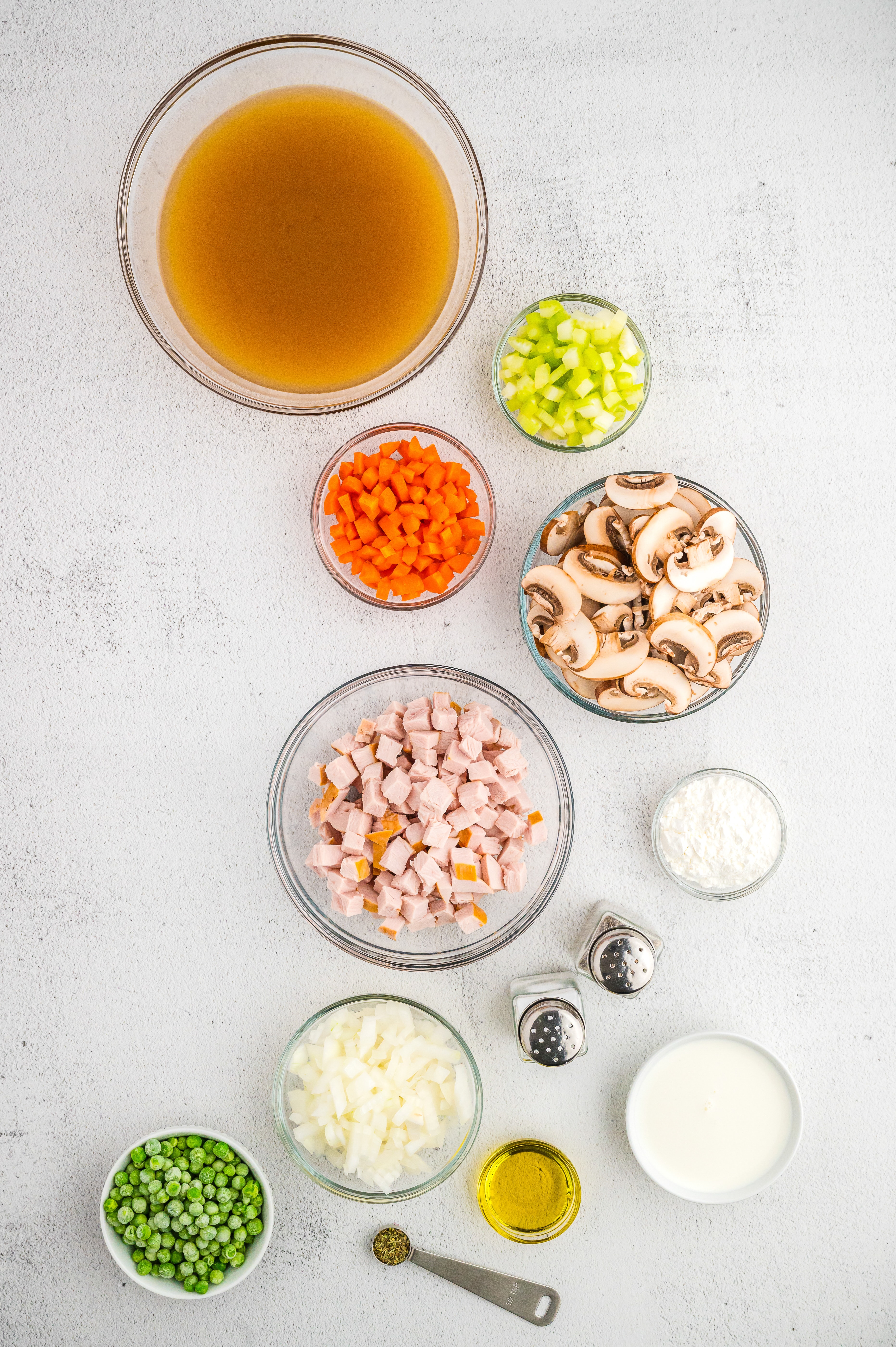Measured ingredients needed for to make Turkey a la King presented in clear glass prep bowls.