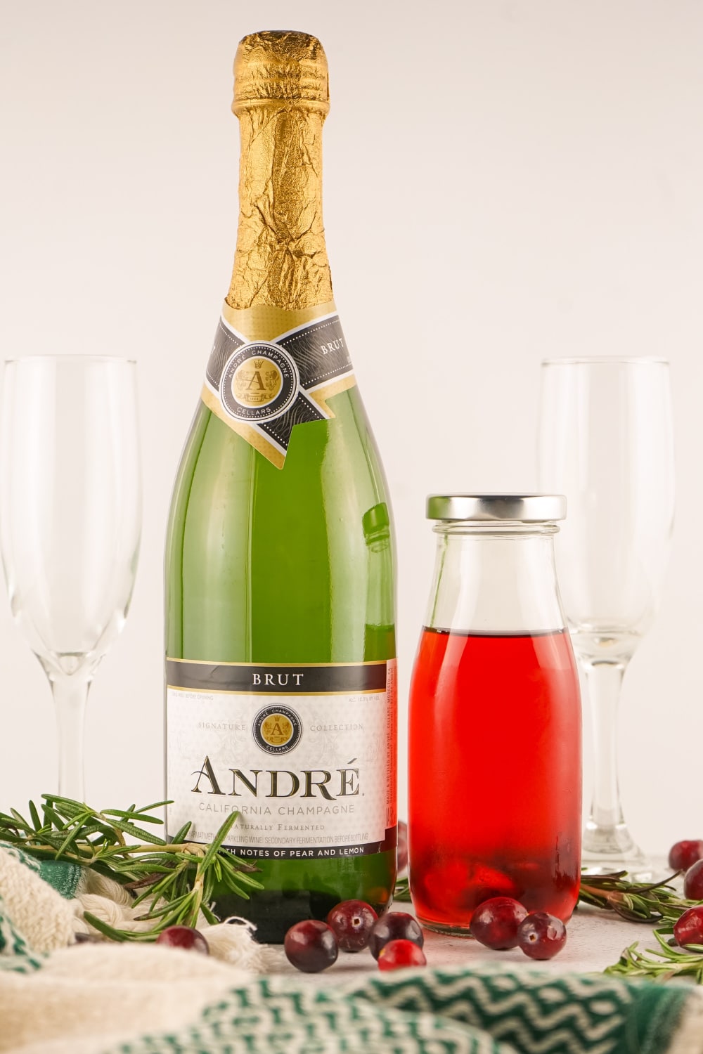 A bottle of champagne and a carafe of cranberry juice on a white countertop.