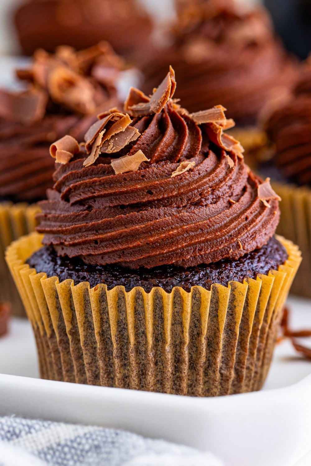 A Chocolate Bailey's Cupcake in paper wrapper sitting on a white countertop.