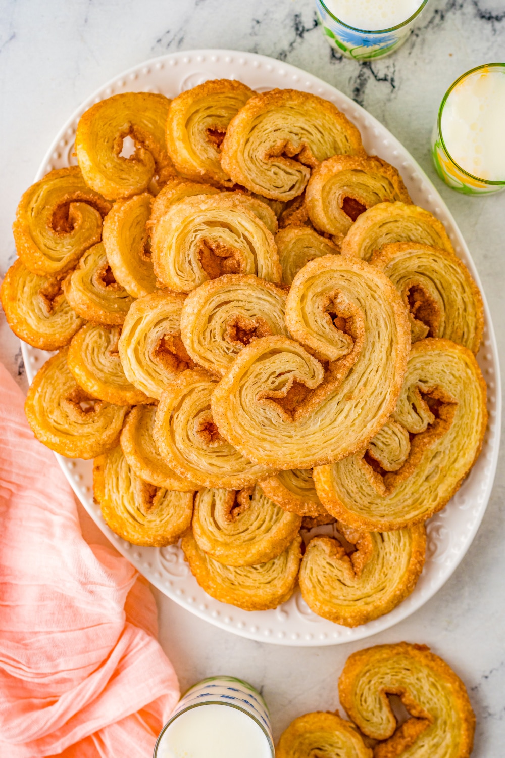A white platter plied high with Palmiers.