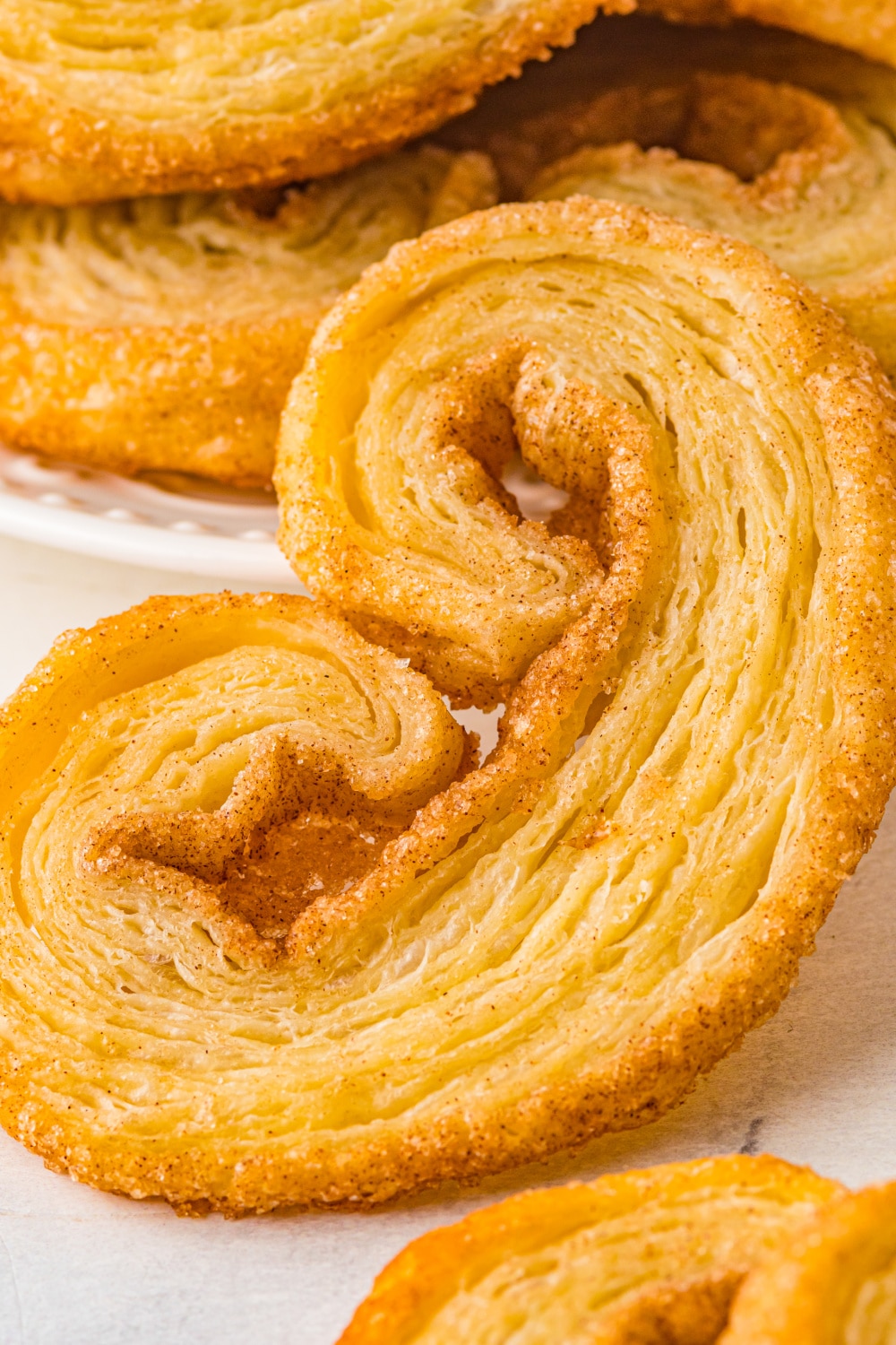 Close up photo shows the layers of puffy pastry on a single Palmier cookie.
