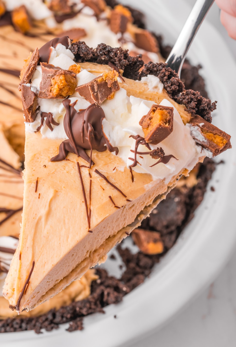 A single piece o pie on a pie server with chopped garnished peanut butter cups.