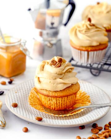 Coffee flavored cupcake with frosting on a white dessert plate.