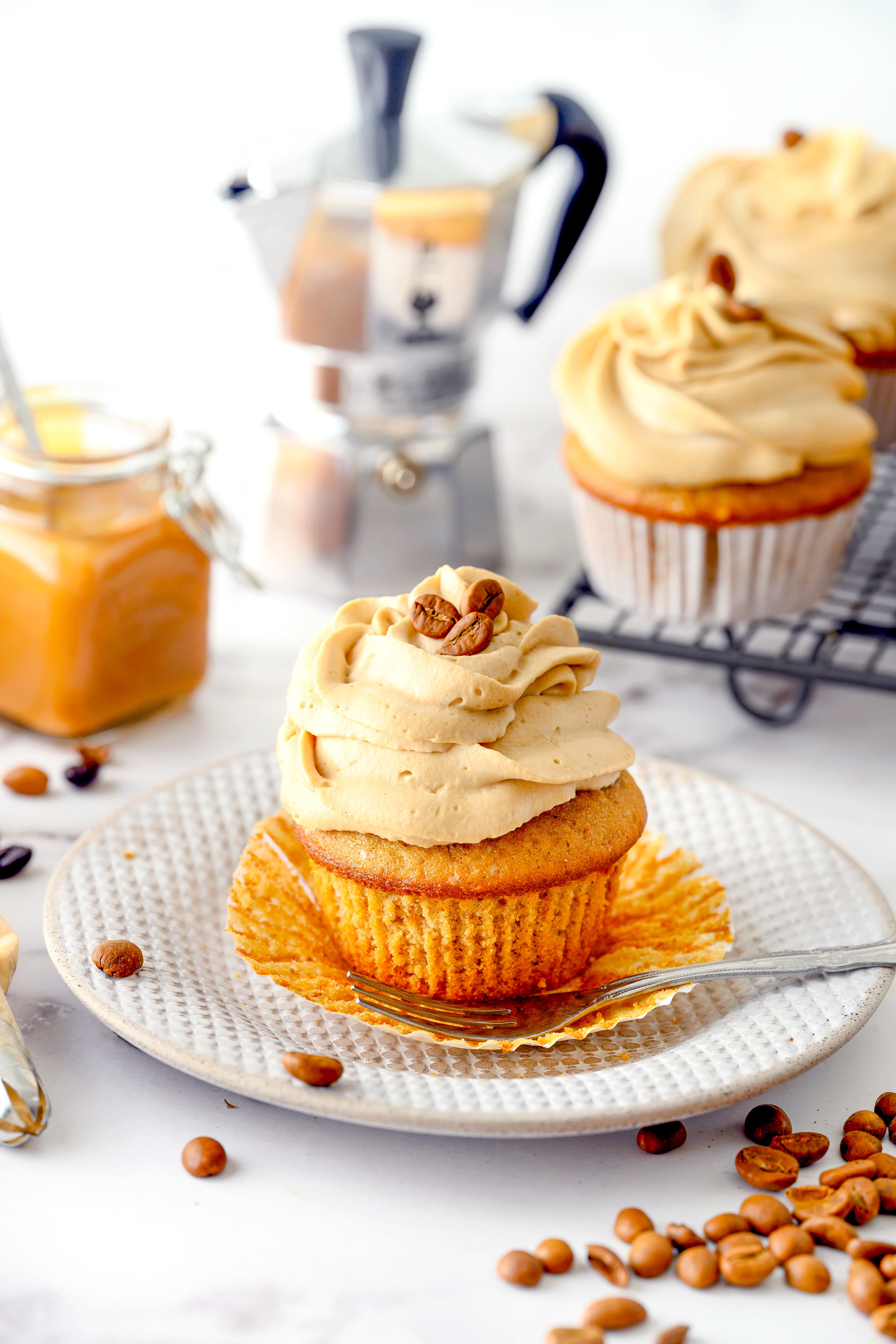 Coffee flavored cupcake with frosting on a white dessert plate.