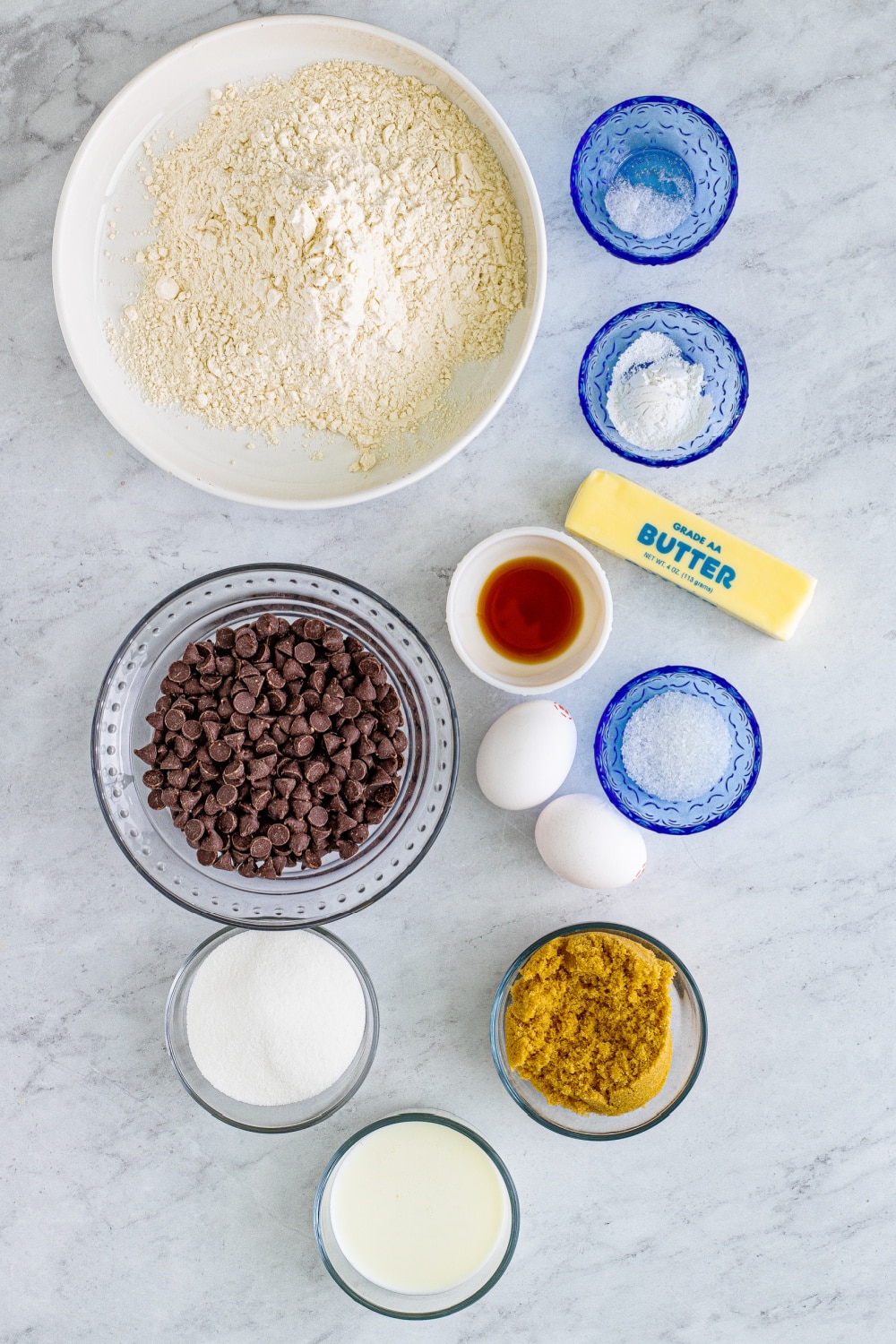 Measured ingredients needed to make these muffins presented in bowls on a white marble countertop.