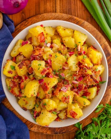 German Potato Salad with bacon and onions served in a white bowl.