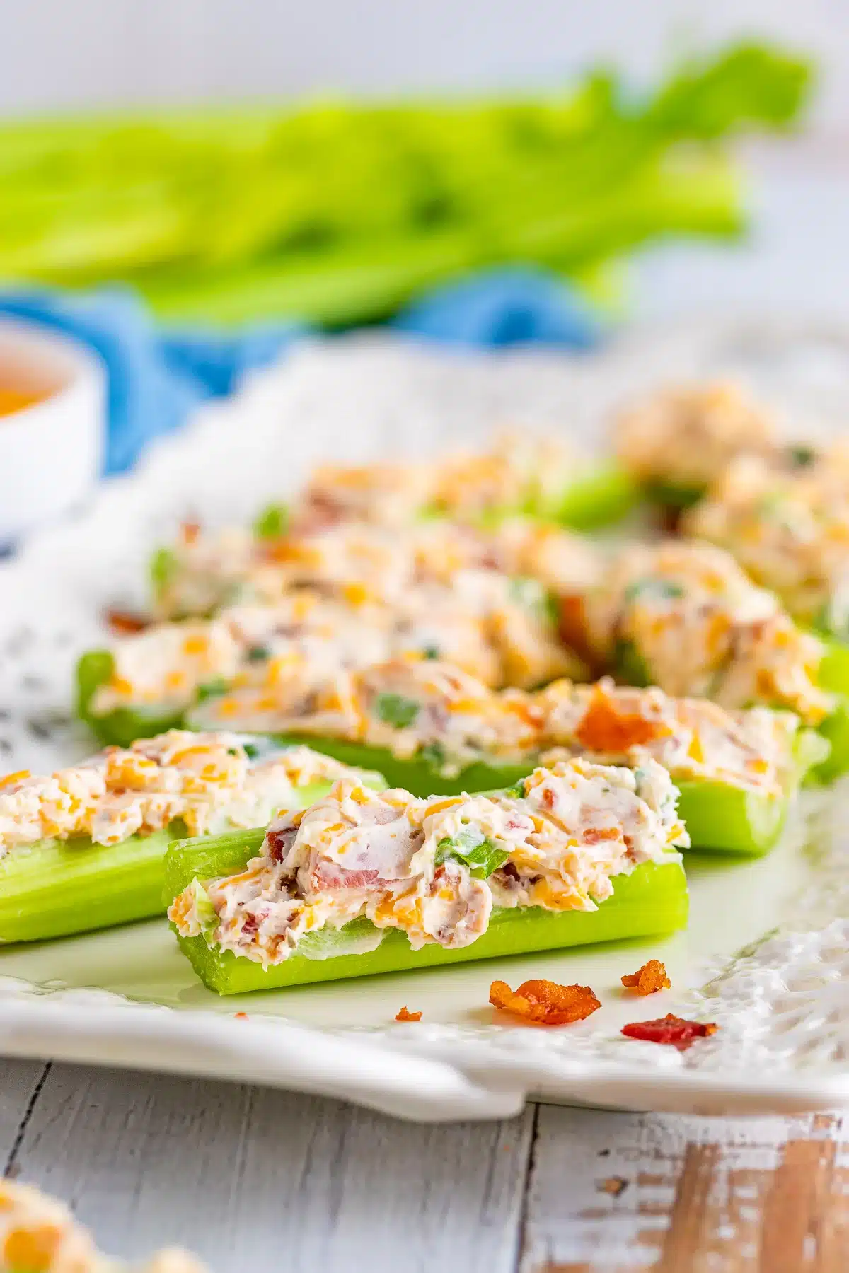 Cream cheese and bacon stuffed celery sticks arranged on a white plate.